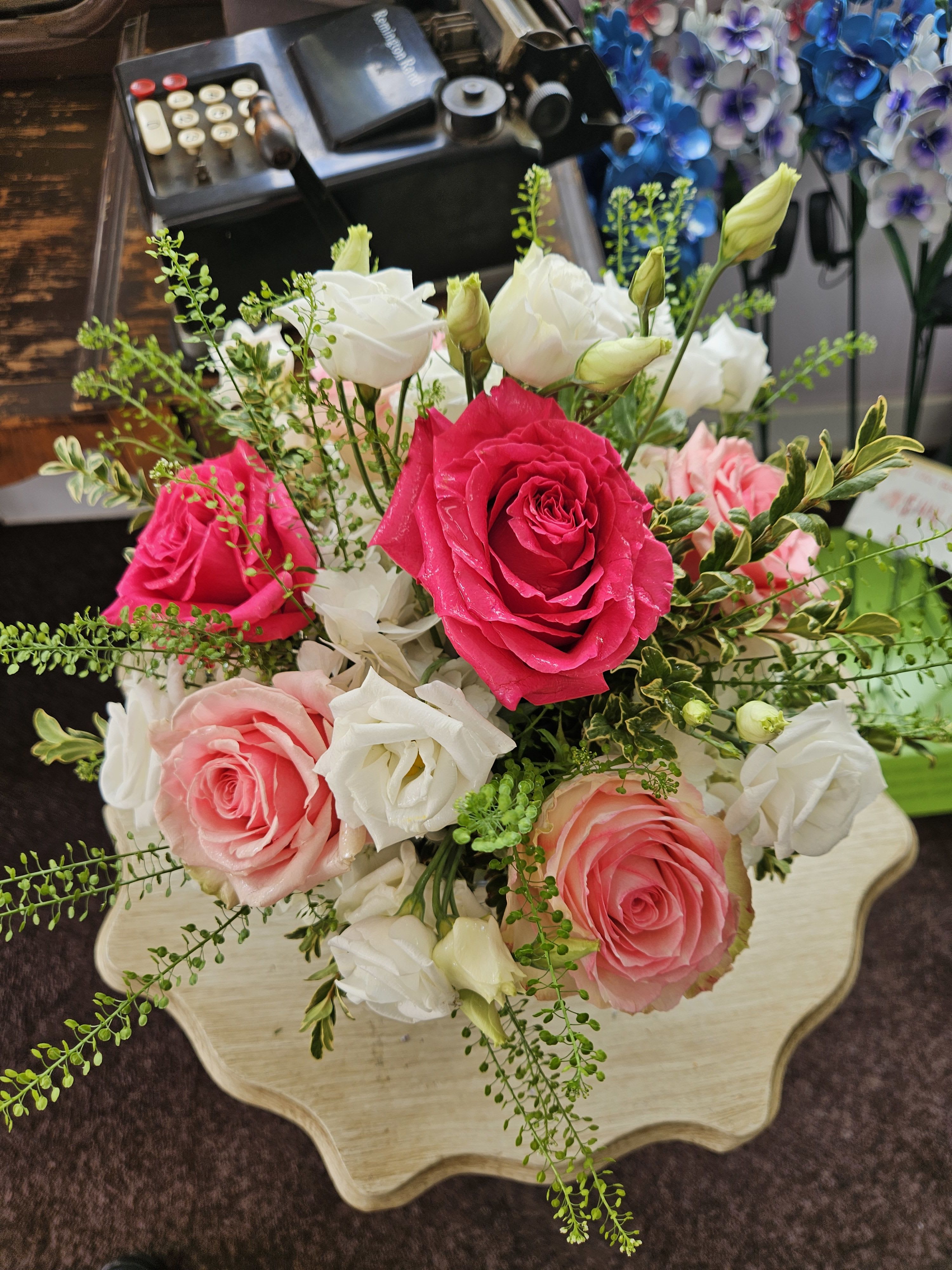 Arrangement of bright pink and peach roses with white lisianthus on a small table