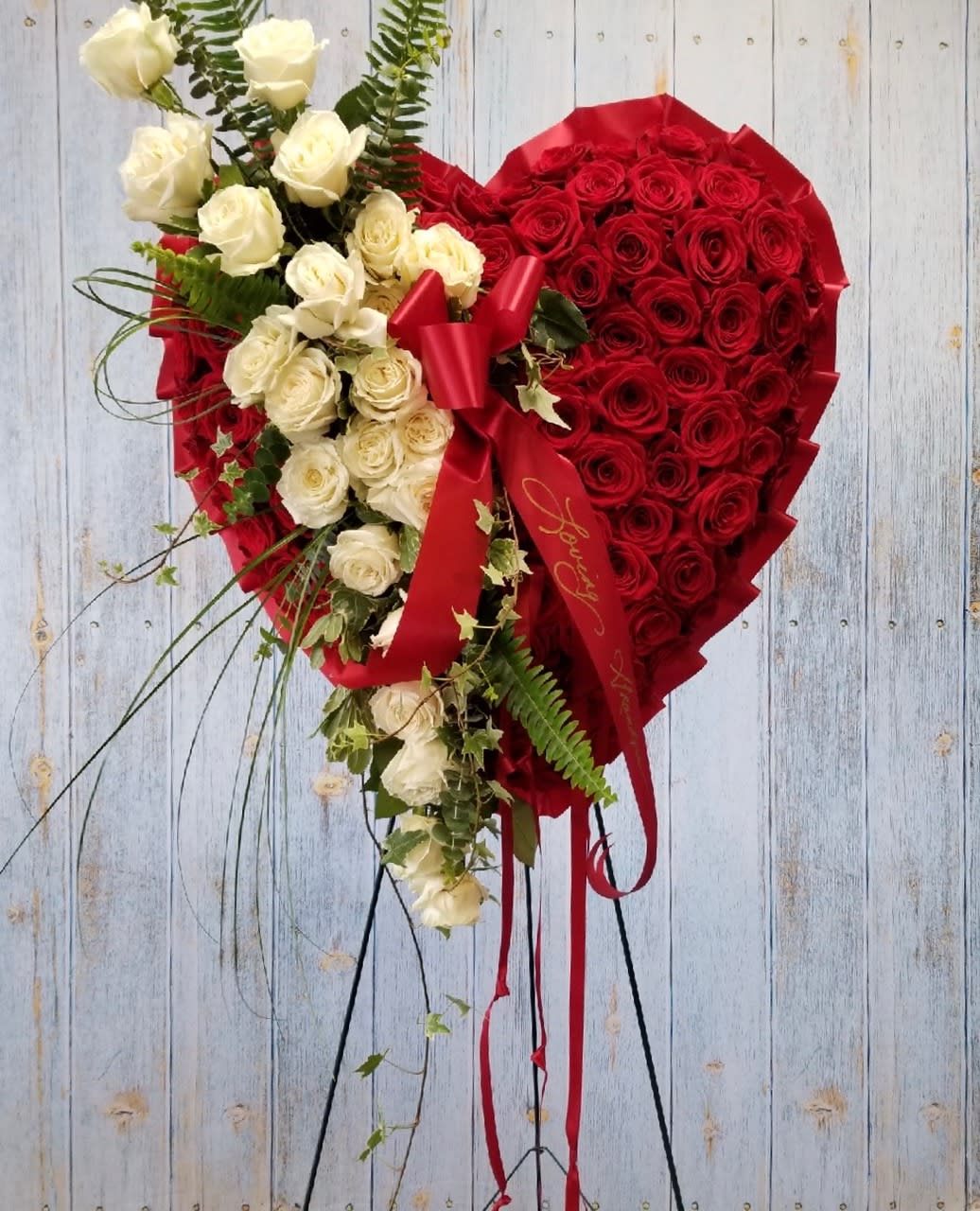 Heart-shaped bouquet of red and white roses with a red ribbon
