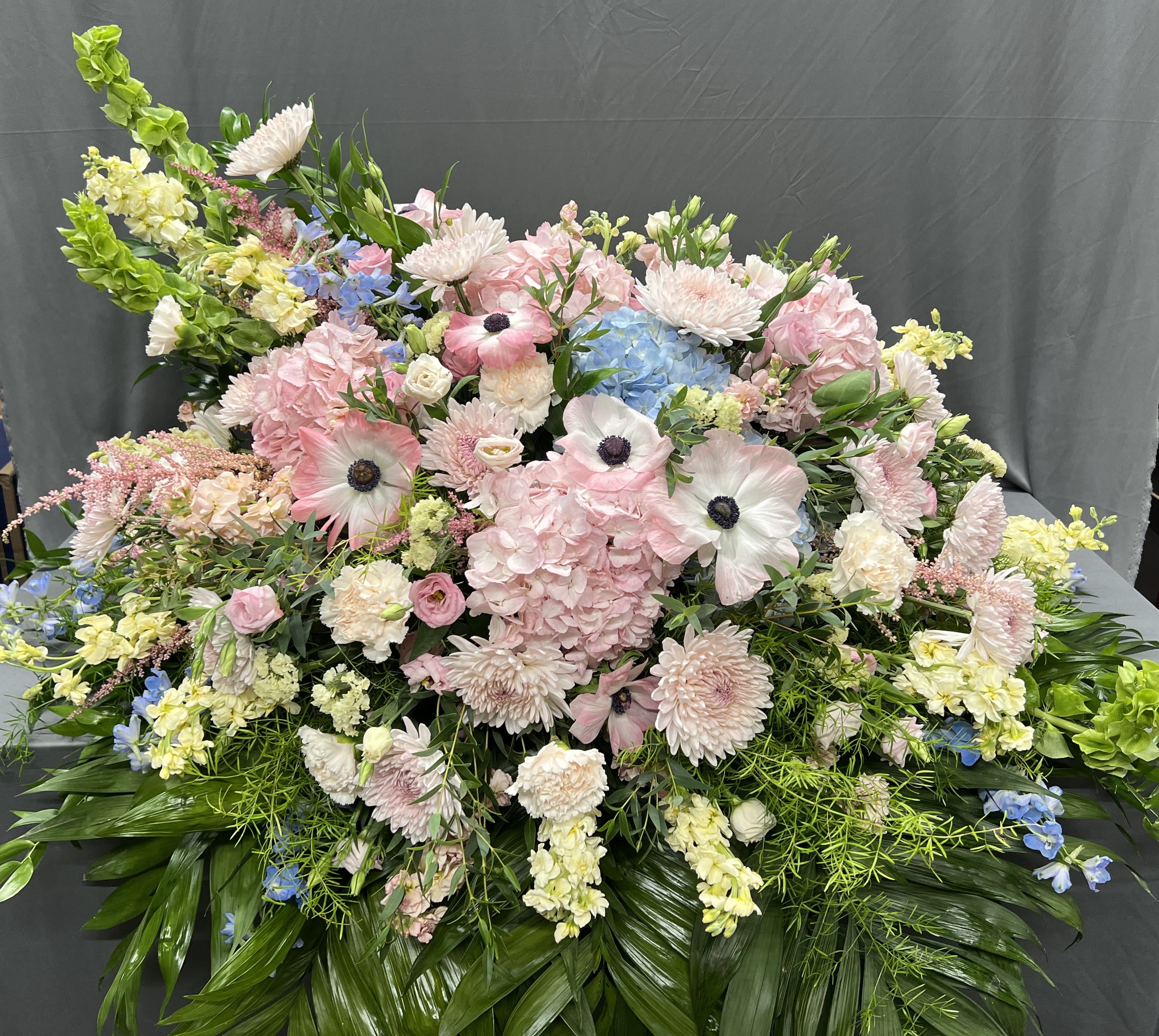 Large pastel floral arrangement with pink, white, blue, and yellow blooms