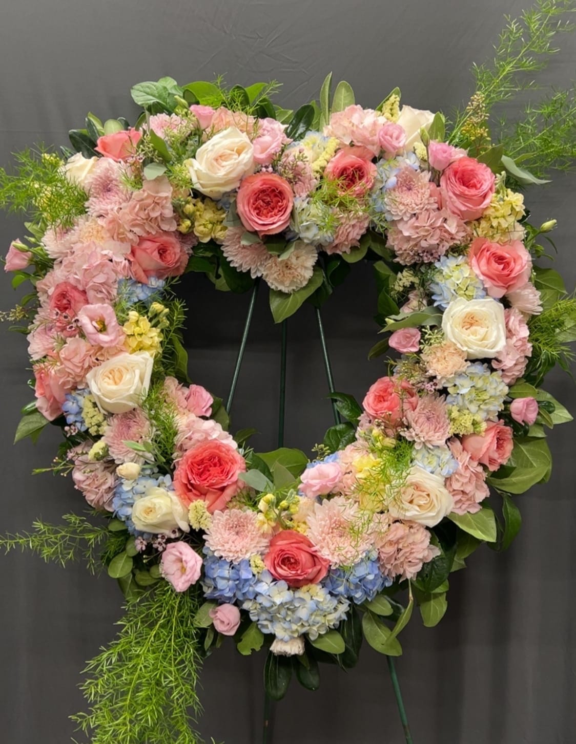 Heart-shaped floral wreath with pink and white roses and pastel blooms