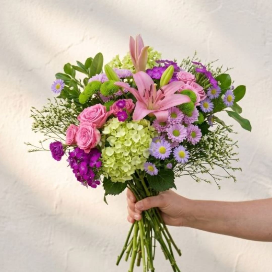 Handheld bouquet of pink lilies, roses, and purple flowers