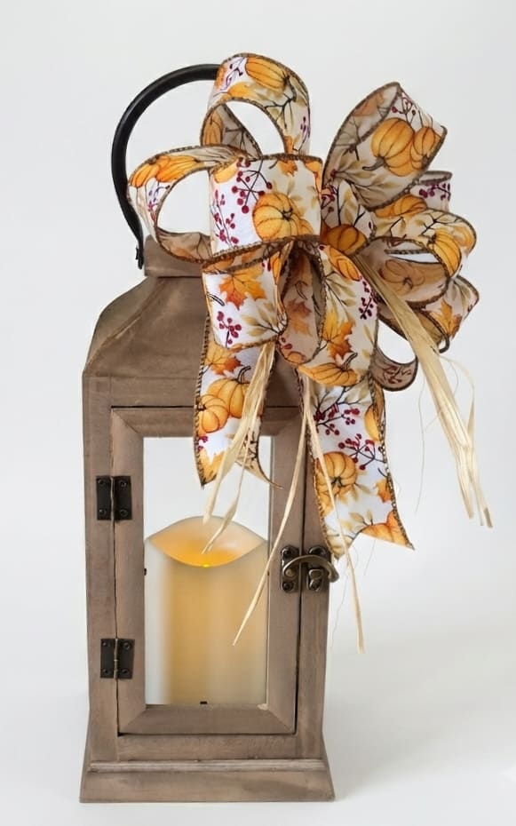 Wooden lantern with a pumpkin-pattern ribbon bow and candle inside