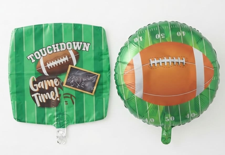 Two green football-themed foil balloons on a white background.
