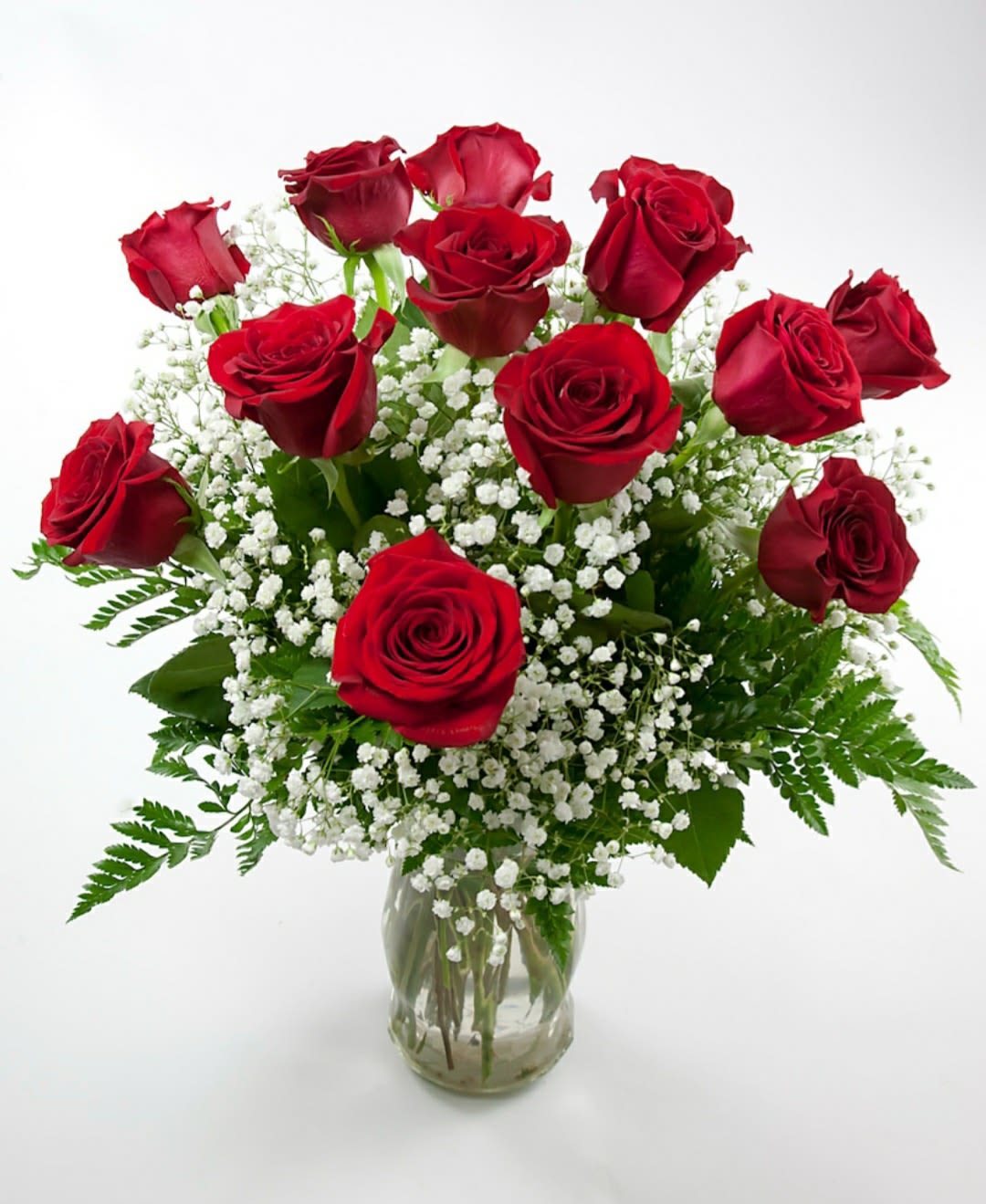 Red roses arranged in a clear glass vase with white baby's breath