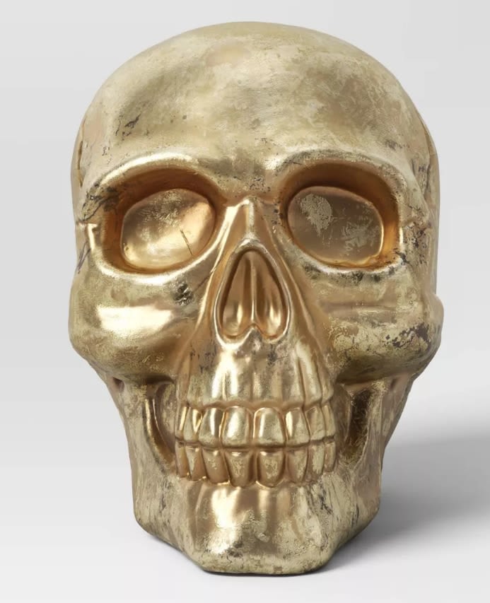 Gold skull decorative object on a plain background