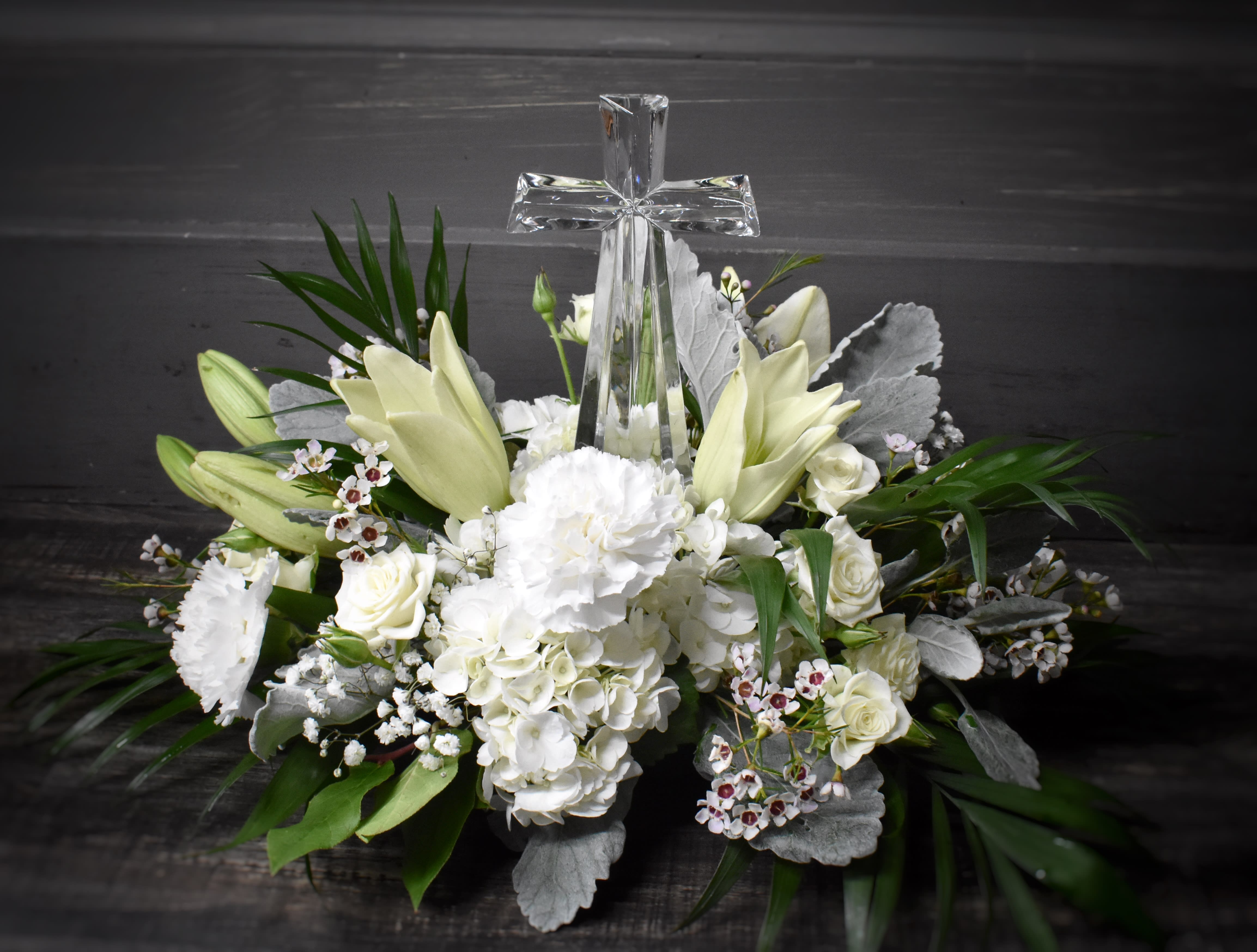 White floral arrangement with a clear glass cross centerpiece