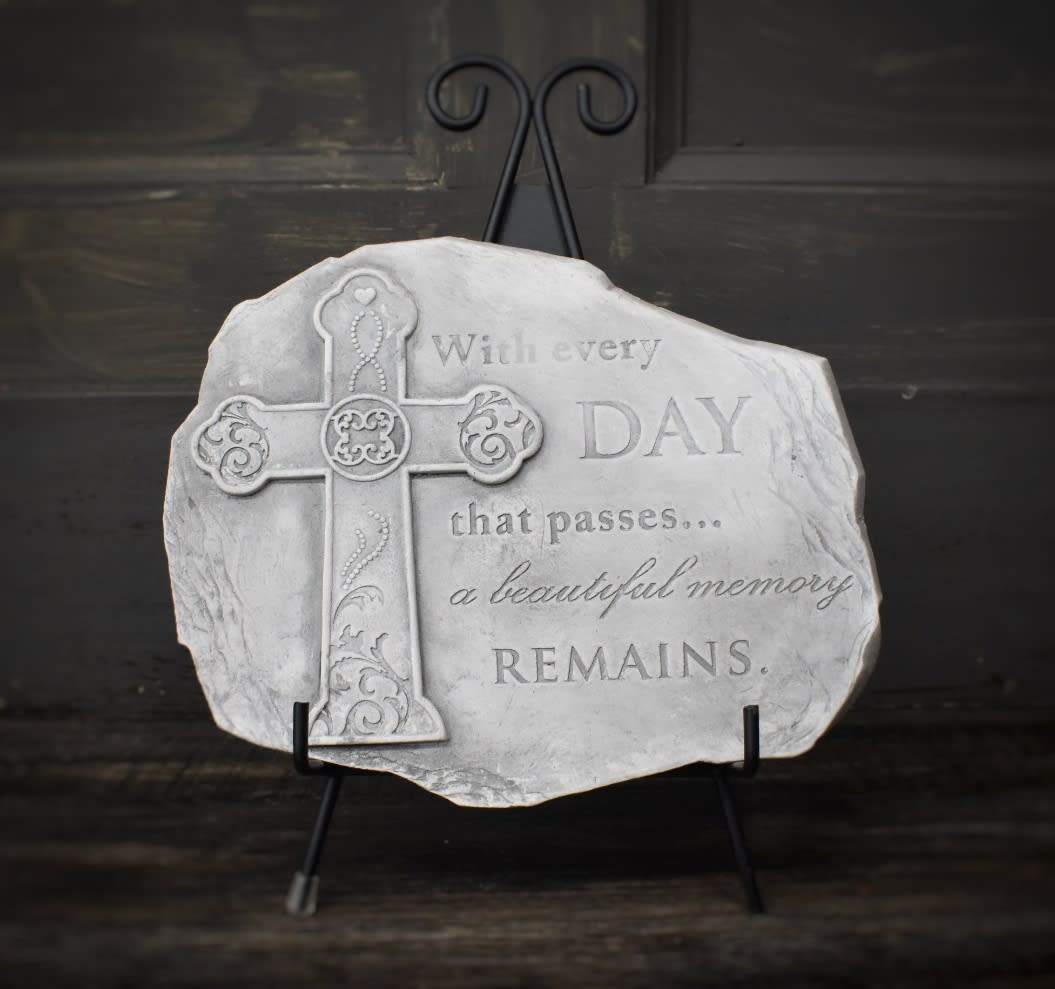 Decorative memorial plaque with a cross and engraved quote on a stand