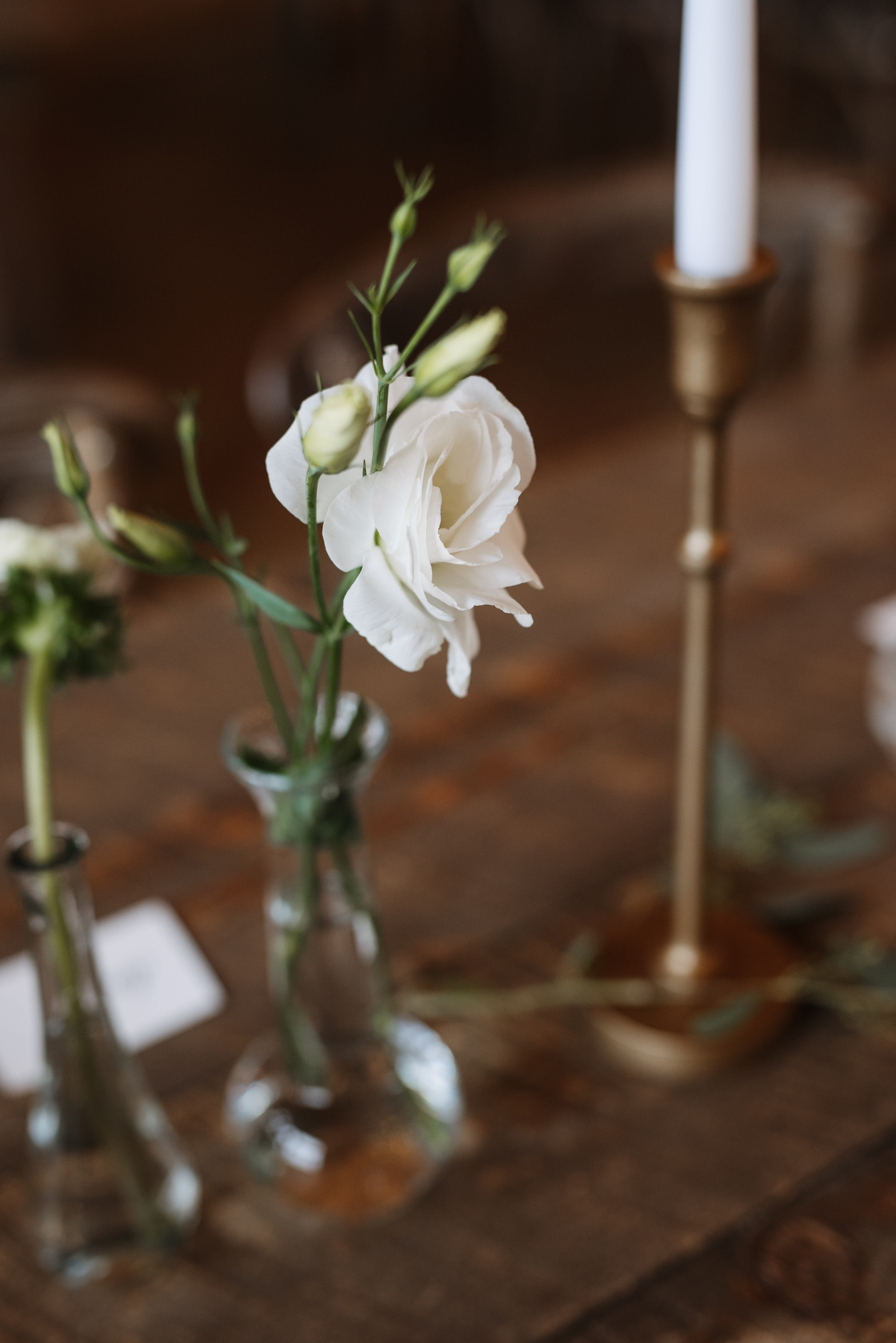 White lisianthus stems in a small glass vase on a table