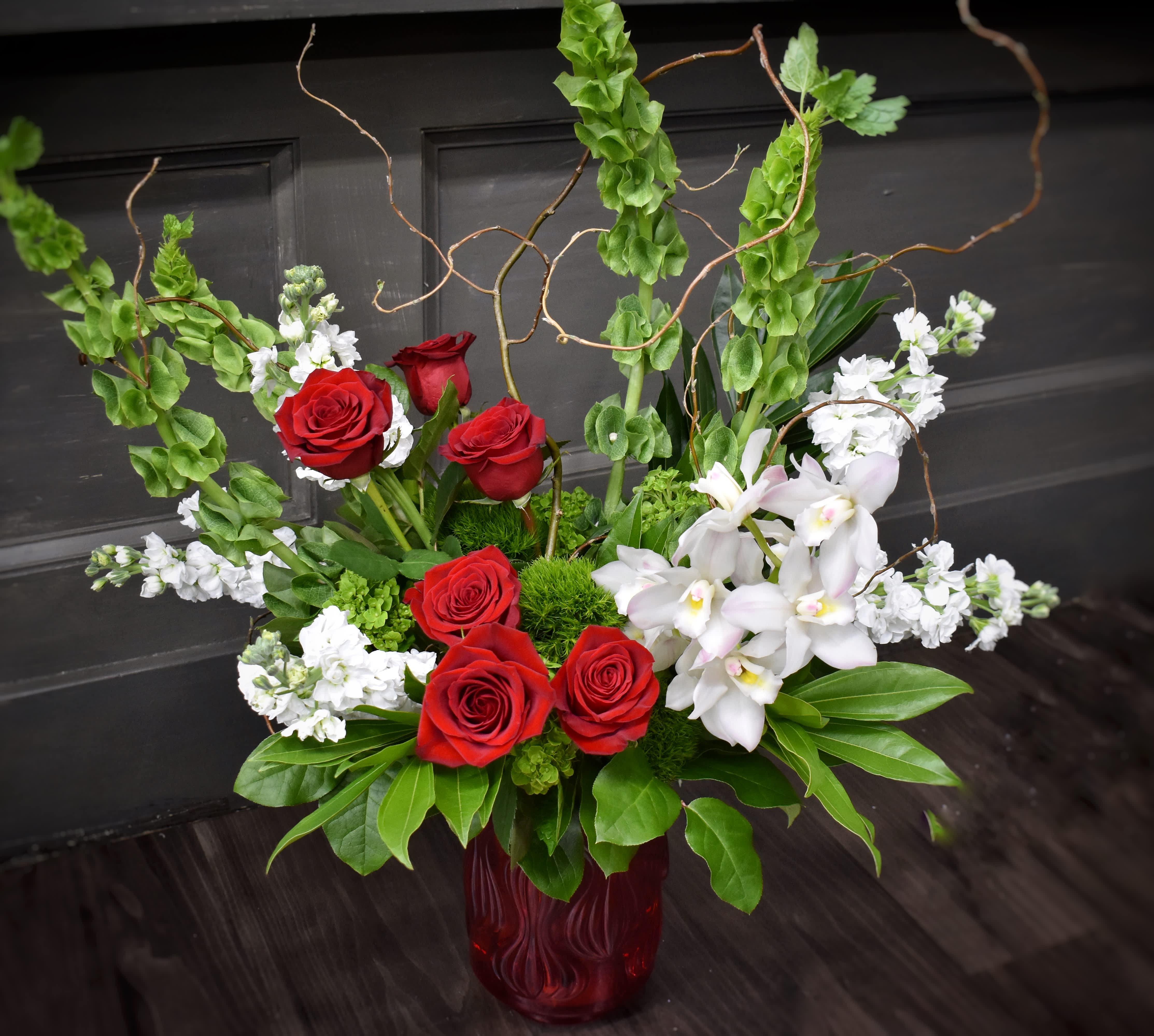 Red roses and white orchids arranged in a red glass vase