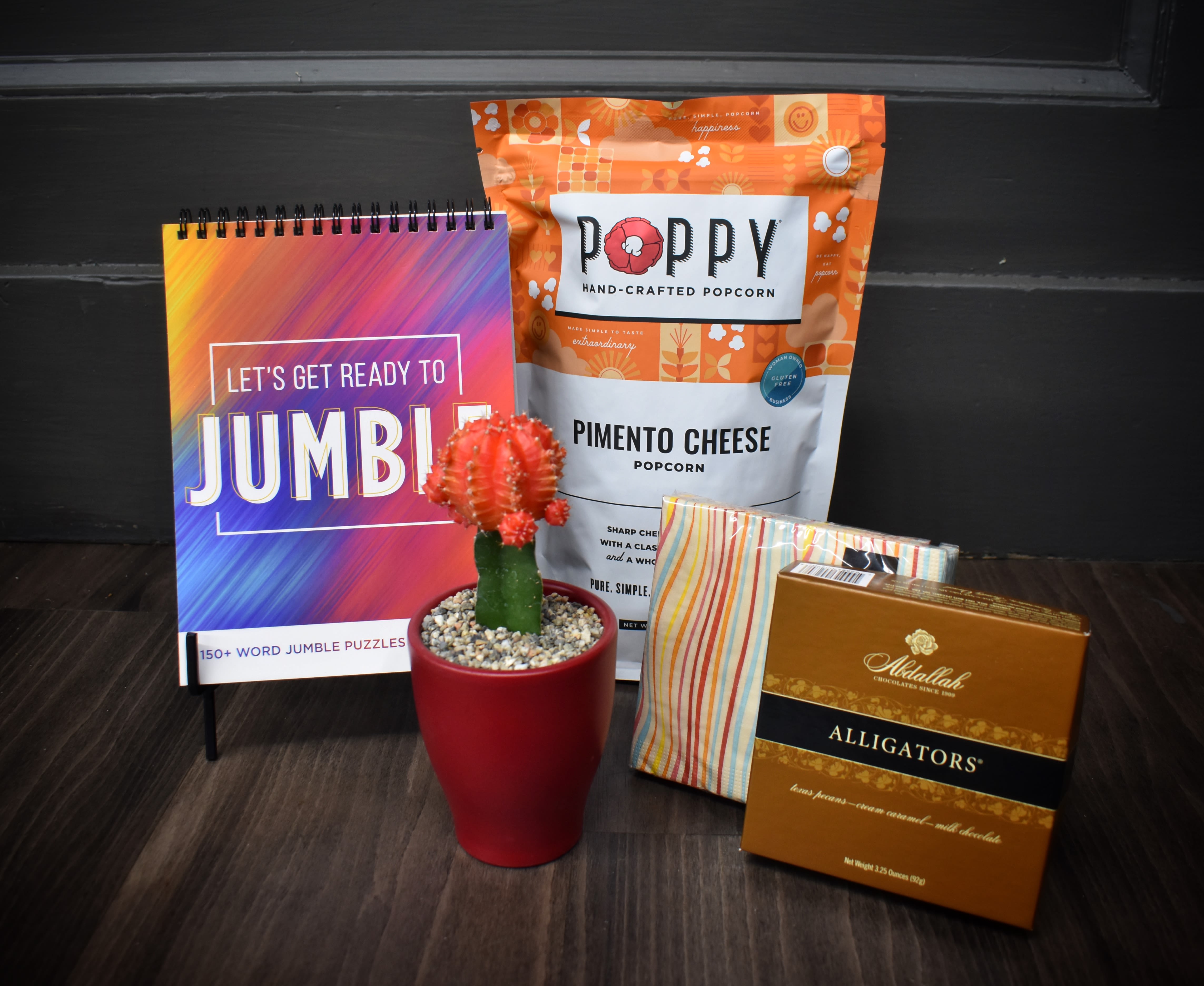 Gift set with a small potted cactus, popcorn, puzzle book, and chocolates