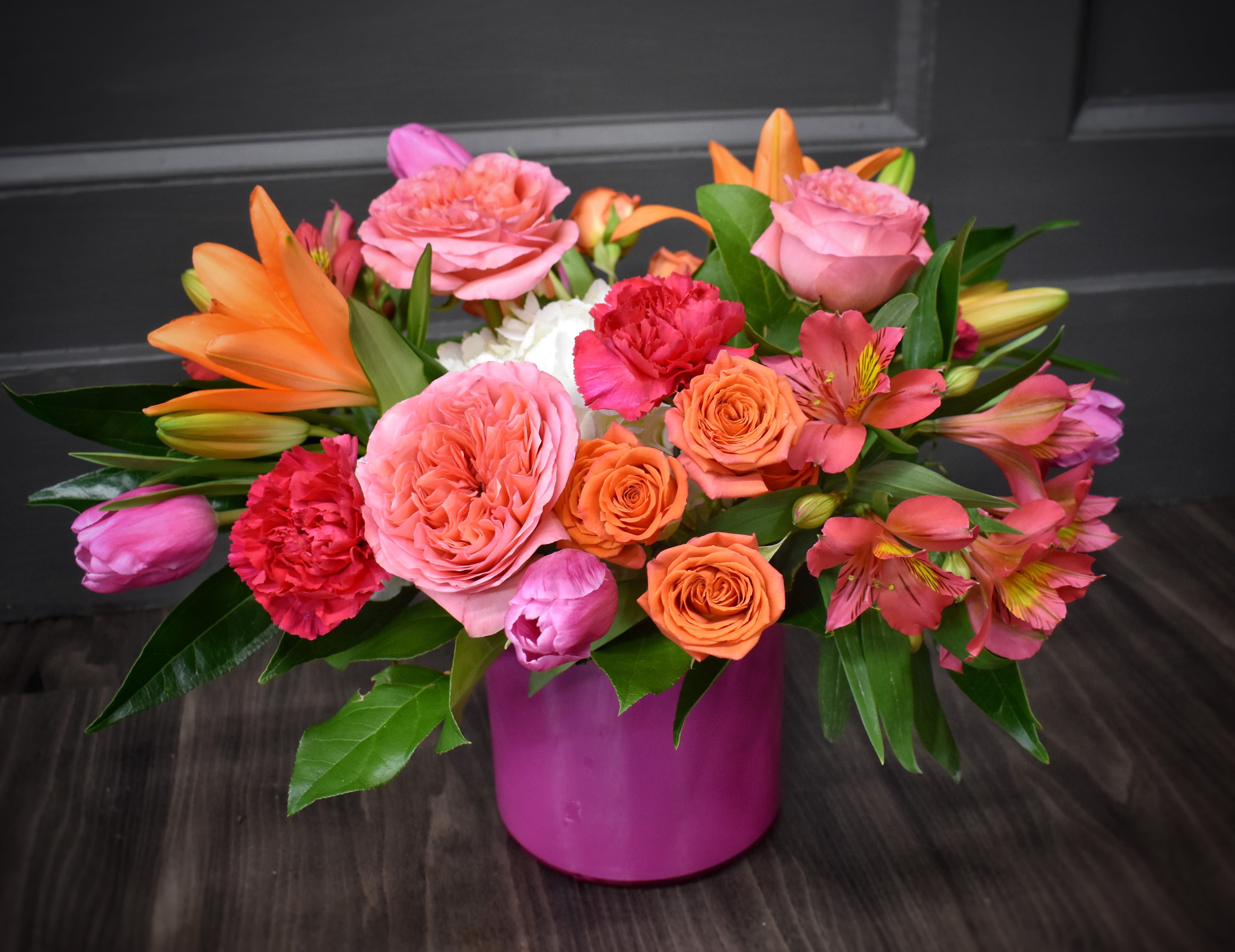 Pink and orange mixed bouquet in a magenta vase