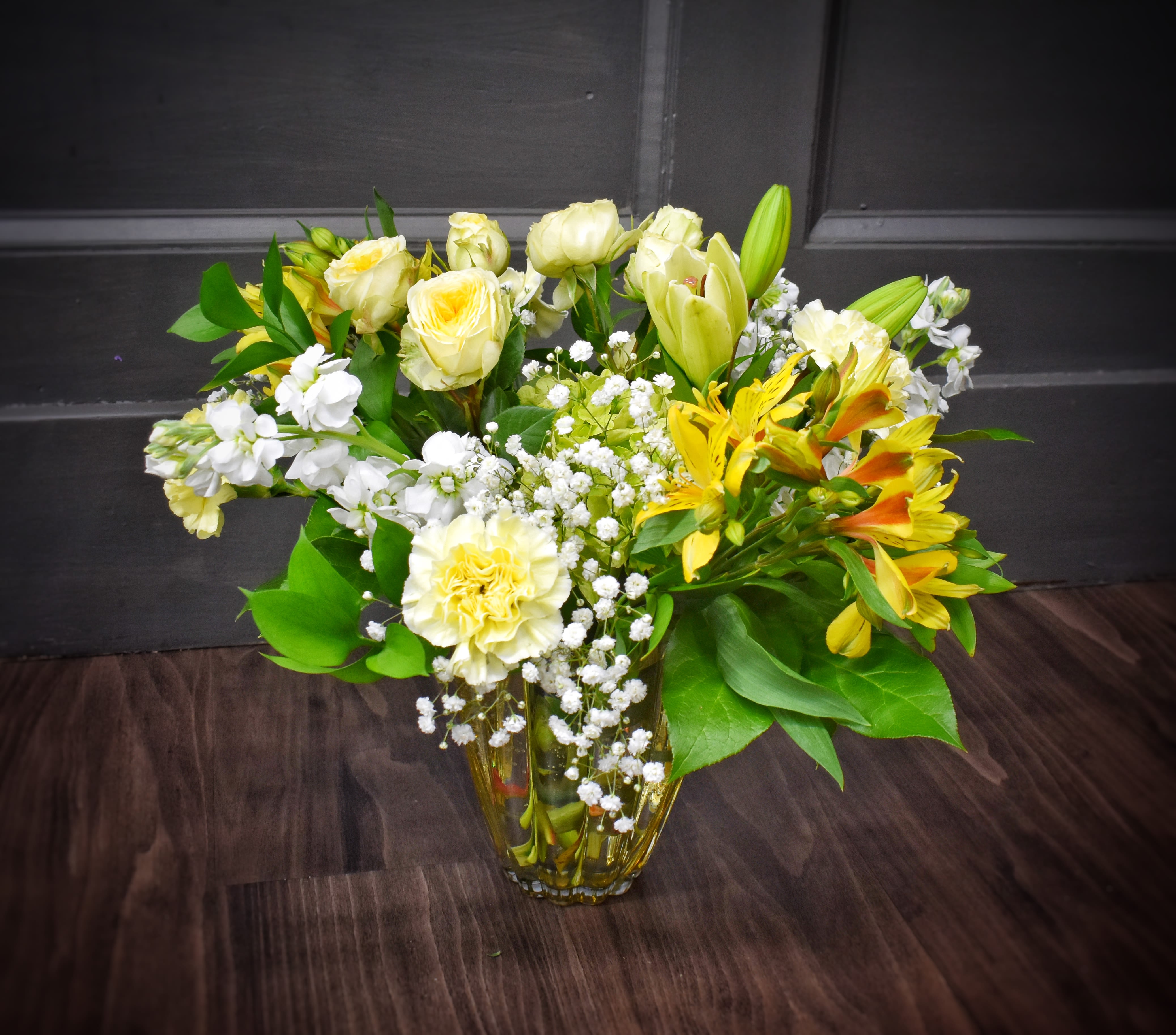 Amber Sunshine - Sunlit yellow roses &amp; yellow alstroemeria combine with creamy white lilies and carnations to create a bright, uplifting flower arrangement perfect for a birthday bouquet, thank-you gift, spring celebration, or a gentle sympathy tribute. The mix of yellow, white, green, and orange blooms reads like a warm morning-she'll feel noticed and comforted by the fresh, optimistic palette.  Ideal for the person who loves sunny, understated elegance-send it to brighten a friend's day, celebrate a milestone, or quietly express your condolences. For best enjoyment, trim stems and change water every 2-3 days; orders can be sized up for larger displays or customized on request.