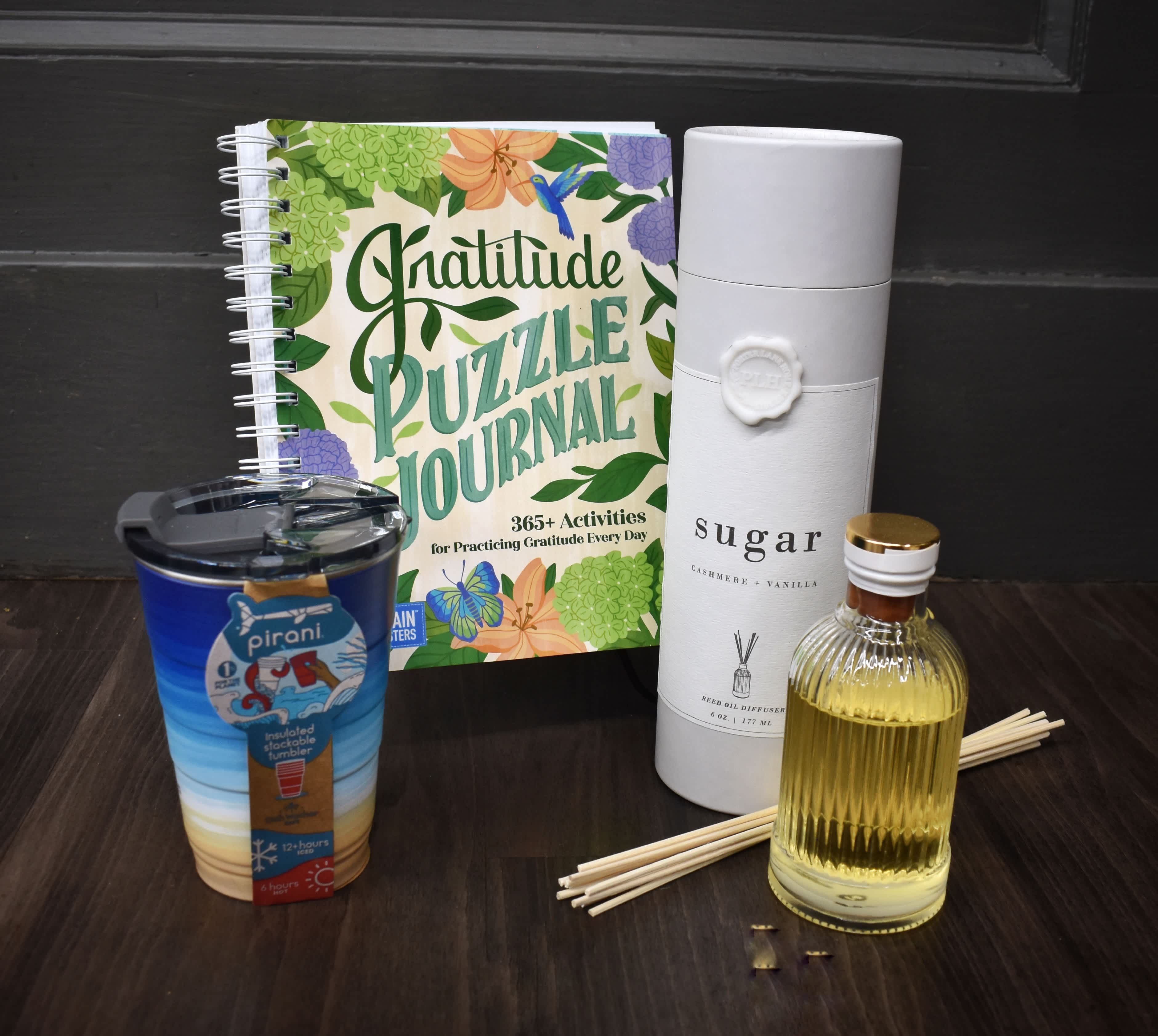 Gift set with a gratitude journal, tumbler, reed diffuser, and small bottle