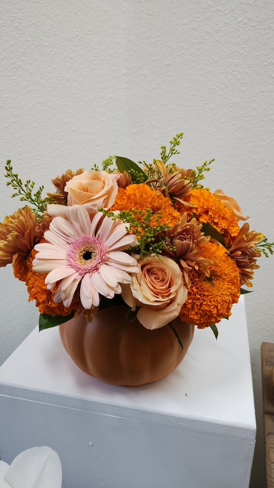 Orange and peach flowers arranged in a pumpkin-shaped vase