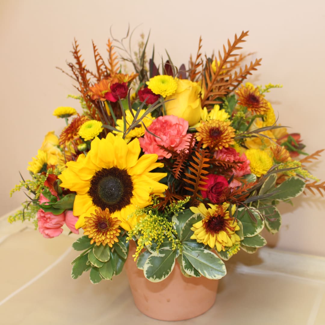 Mixed bouquet with sunflowers, roses, and mums in a peach pot
