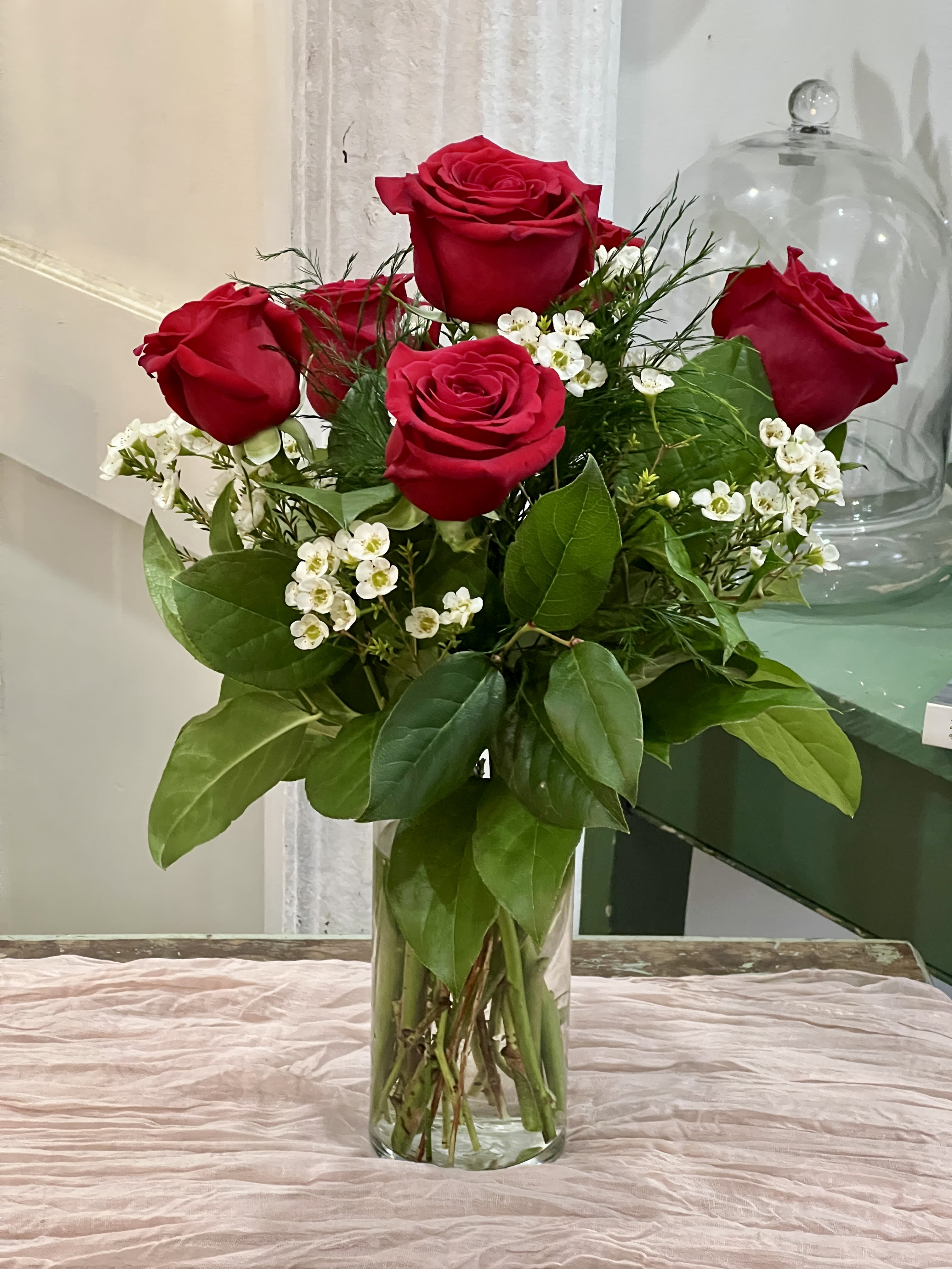 Red roses arranged in a clear glass vase with white filler flowers