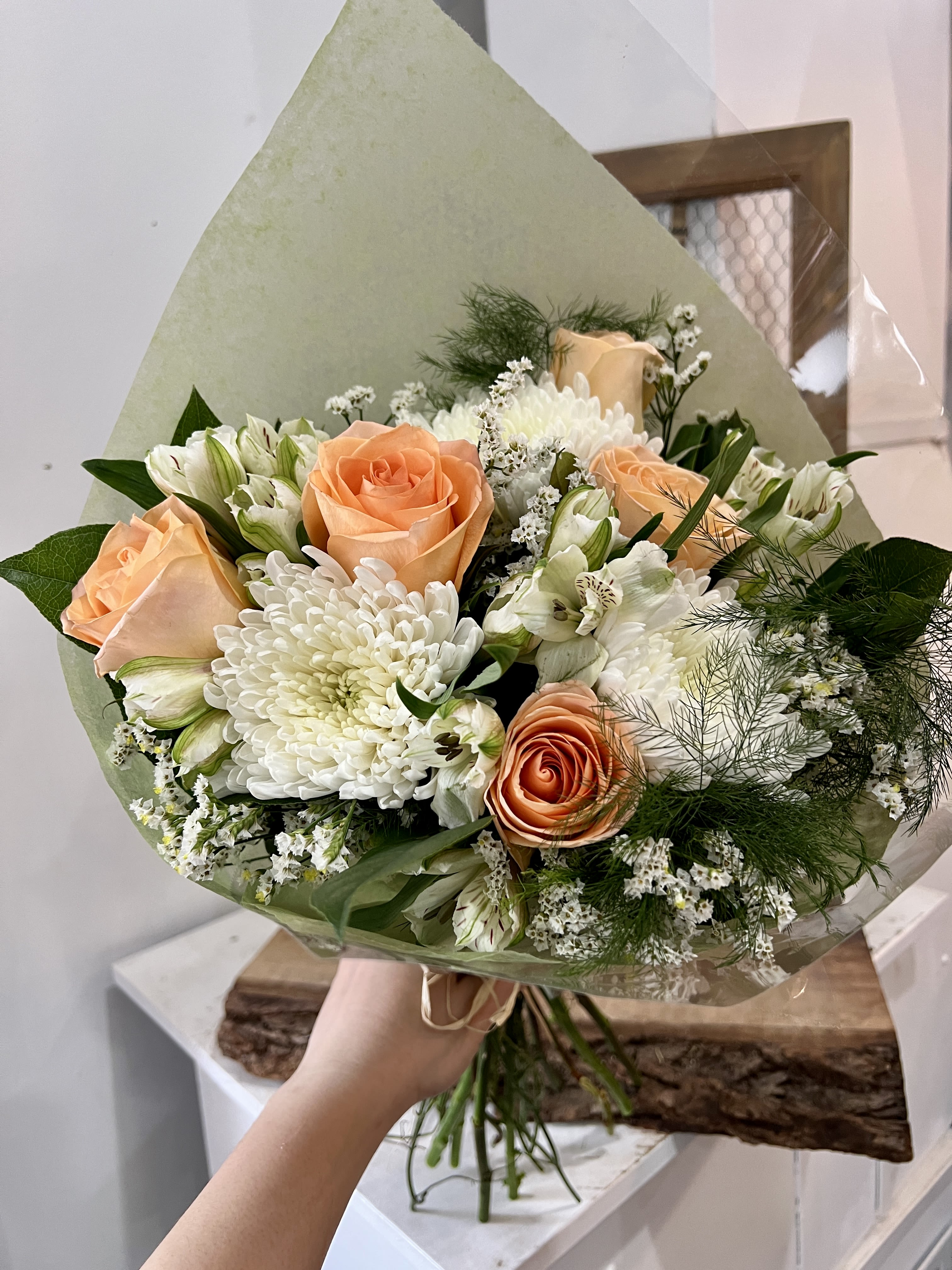 Peach roses and white chrysanthemums in a wrapped bouquet