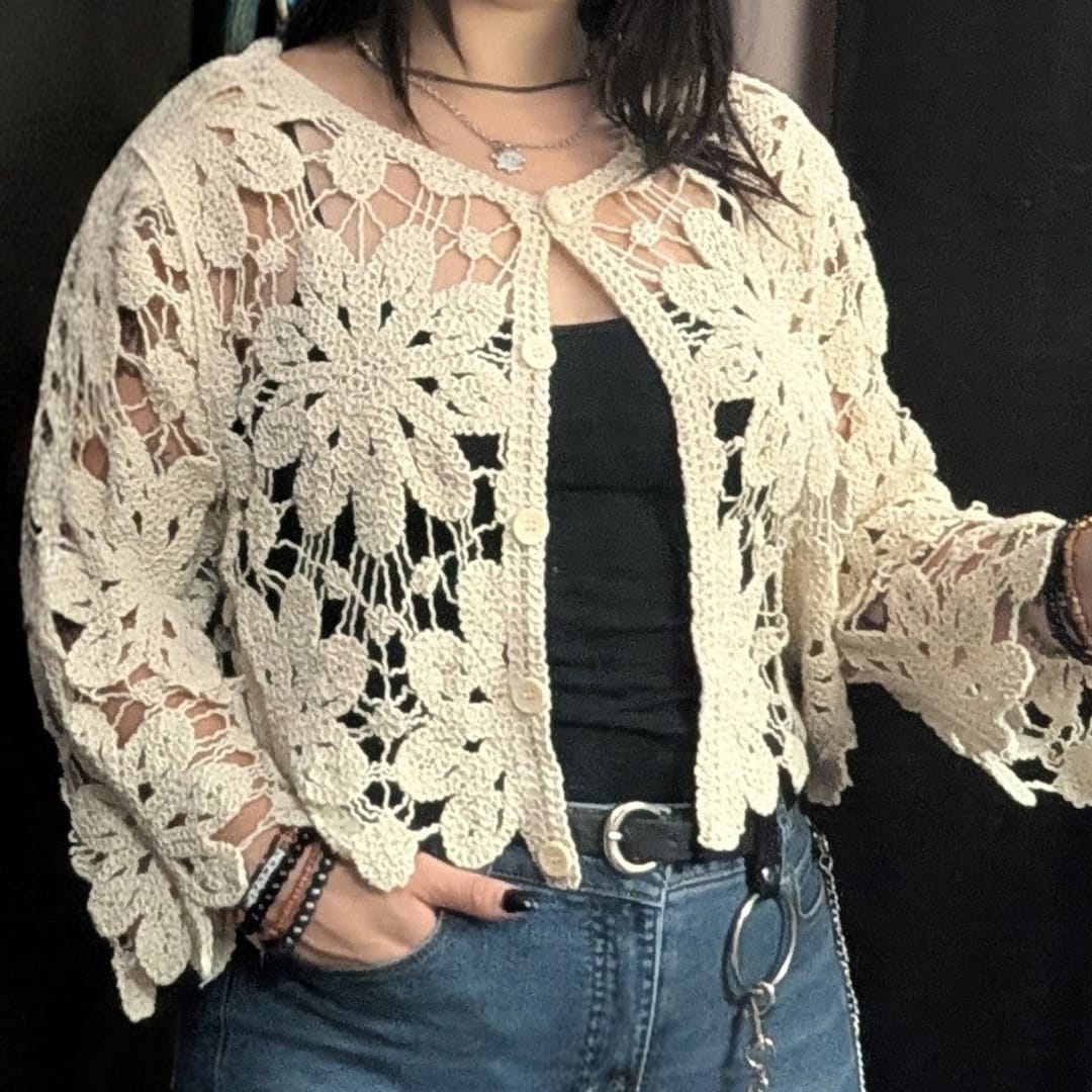 Woman wearing a cream crochet lace cardigan over a black top and jeans