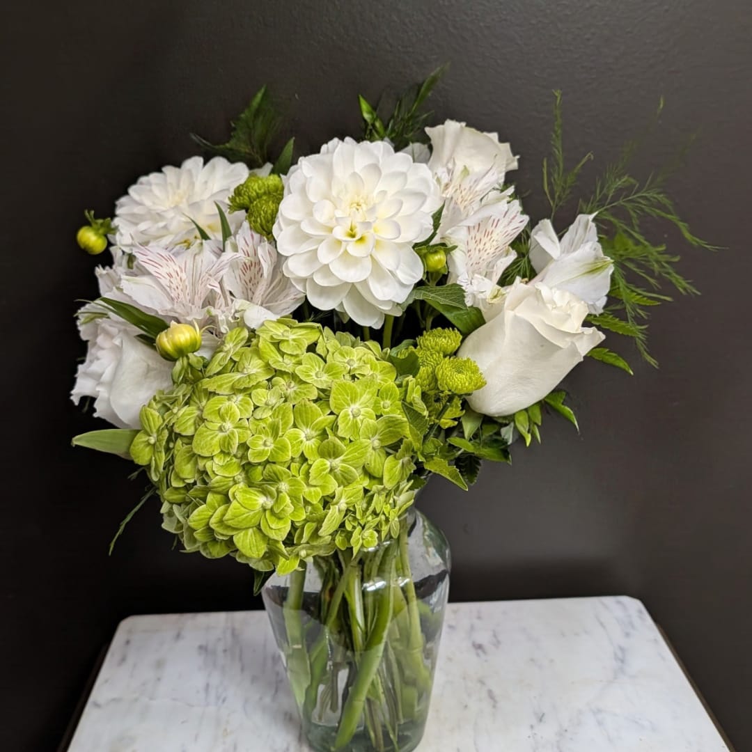 White and green floral arrangement in a clear glass vase