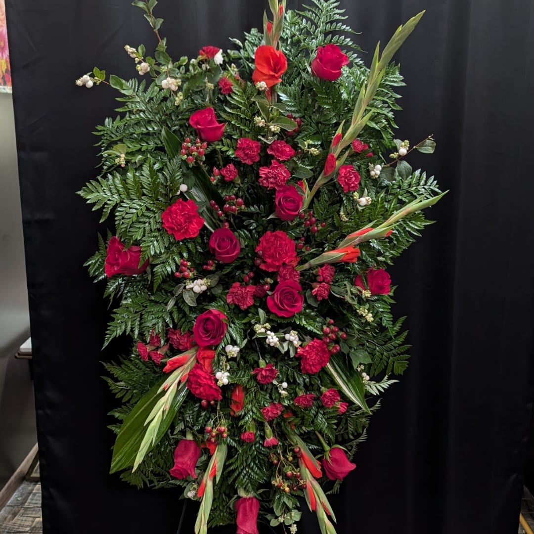 Large standing floral spray with red roses and carnations on dark backdrop
