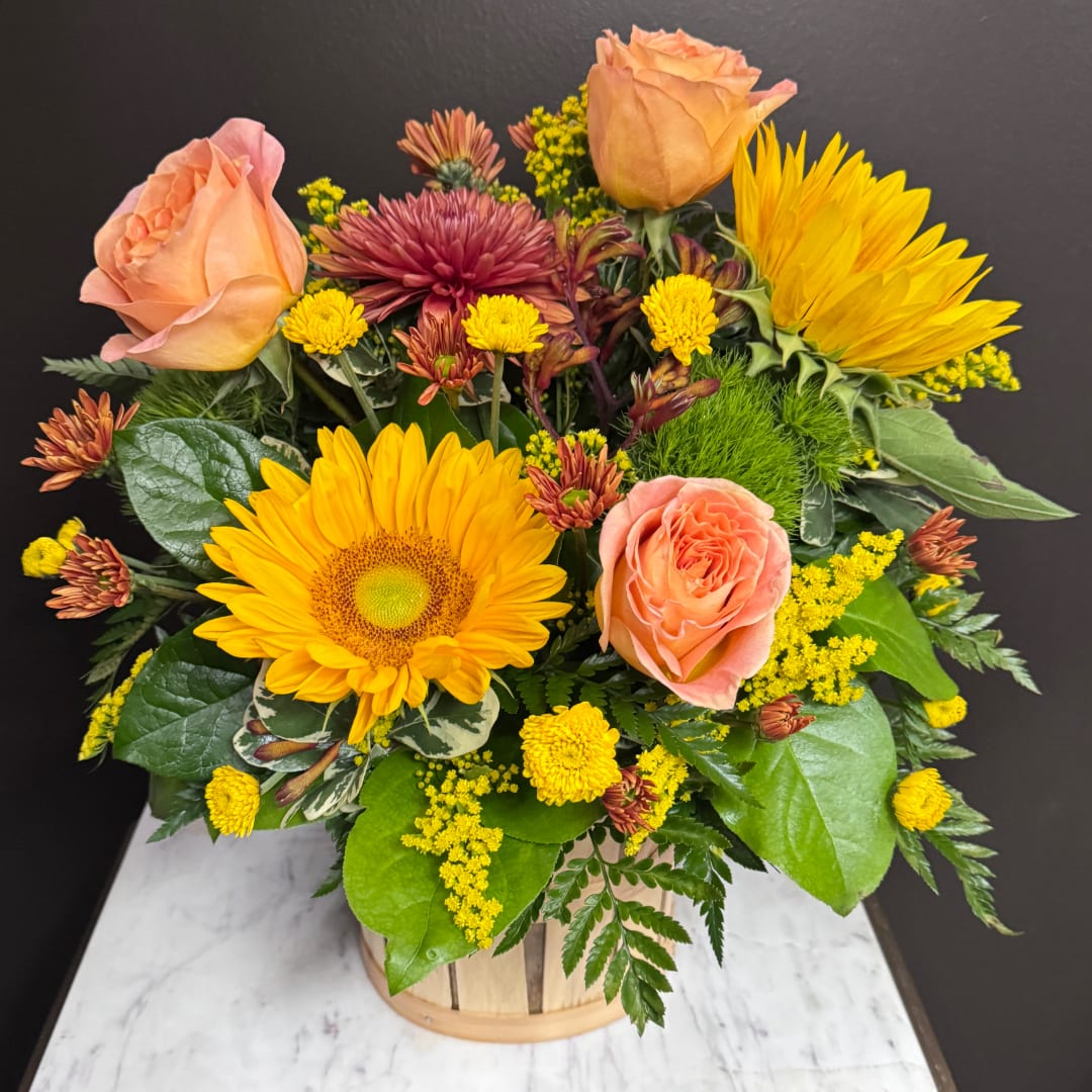 Peach roses and yellow sunflowers in a wooden basket arrangement