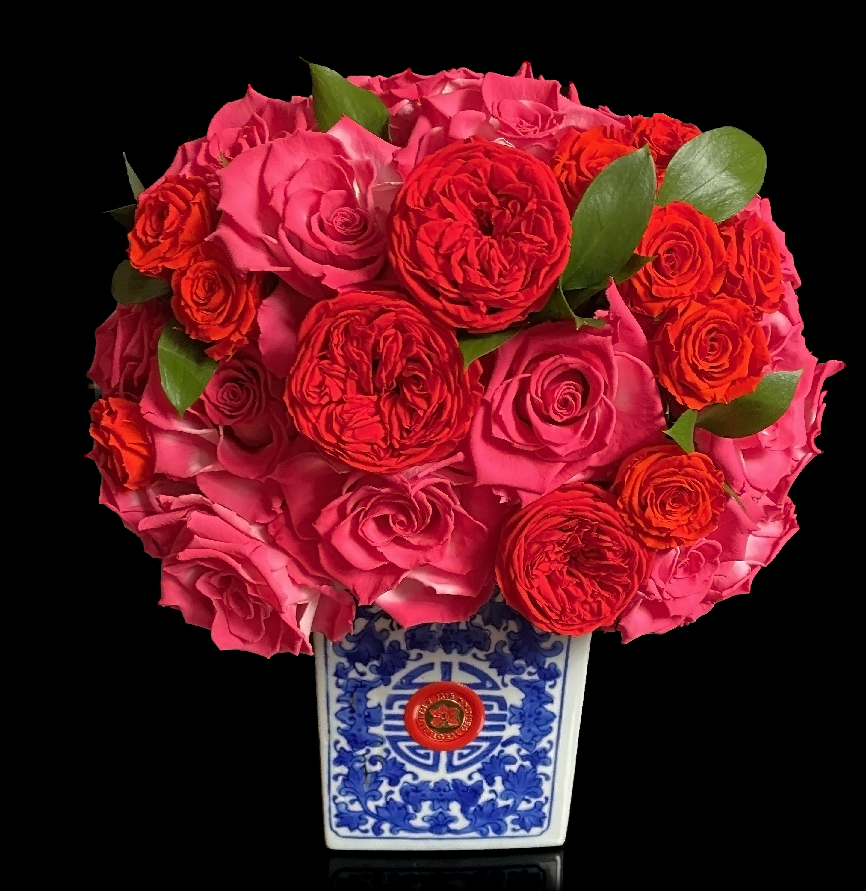 Pink and red rose bouquet in a blue-and-white ceramic vase