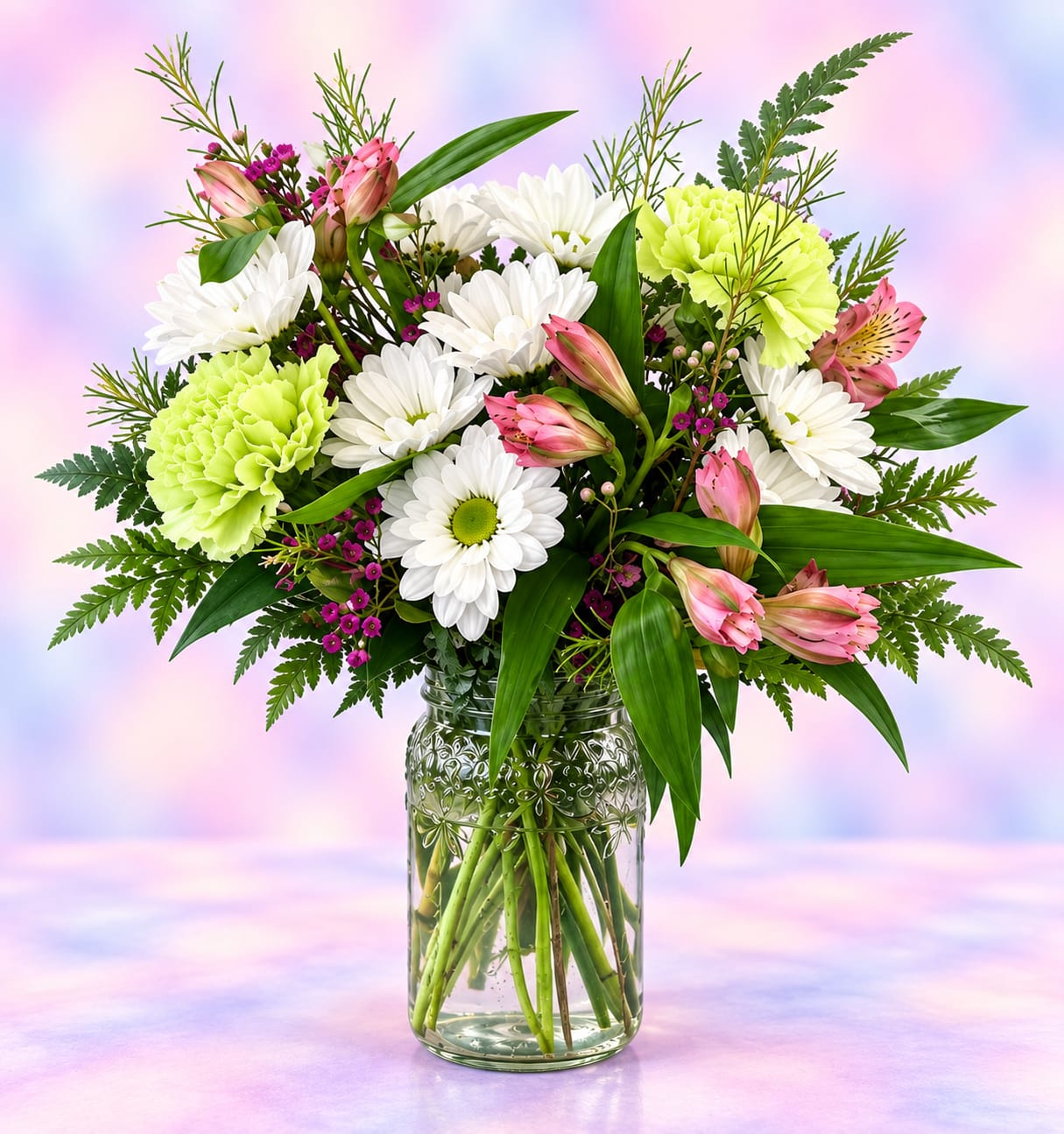 Mixed bouquet of white daisies, pink lilies, and green carnations in a glass jar vase