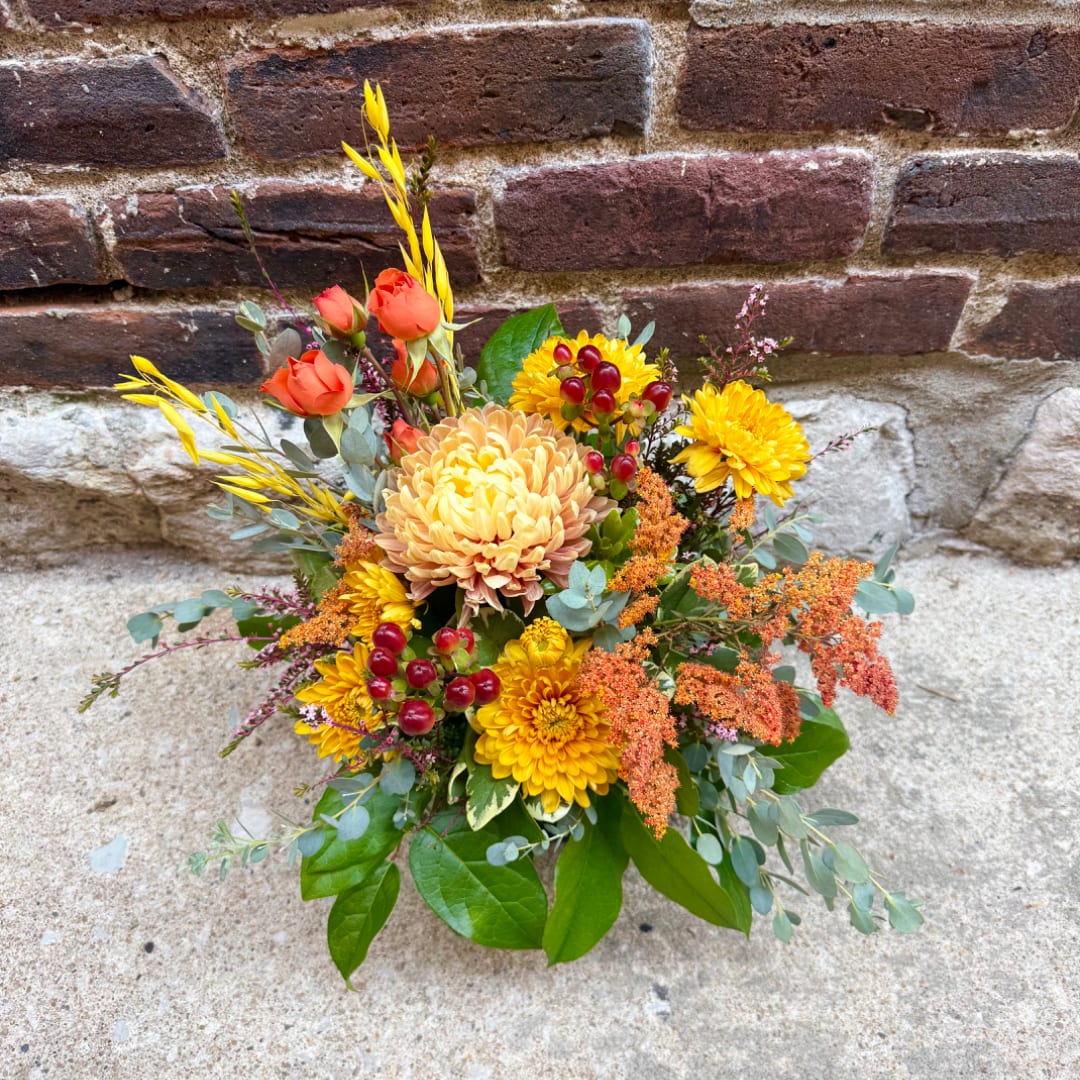 Mixed bouquet with yellow and orange flowers against a brick wall