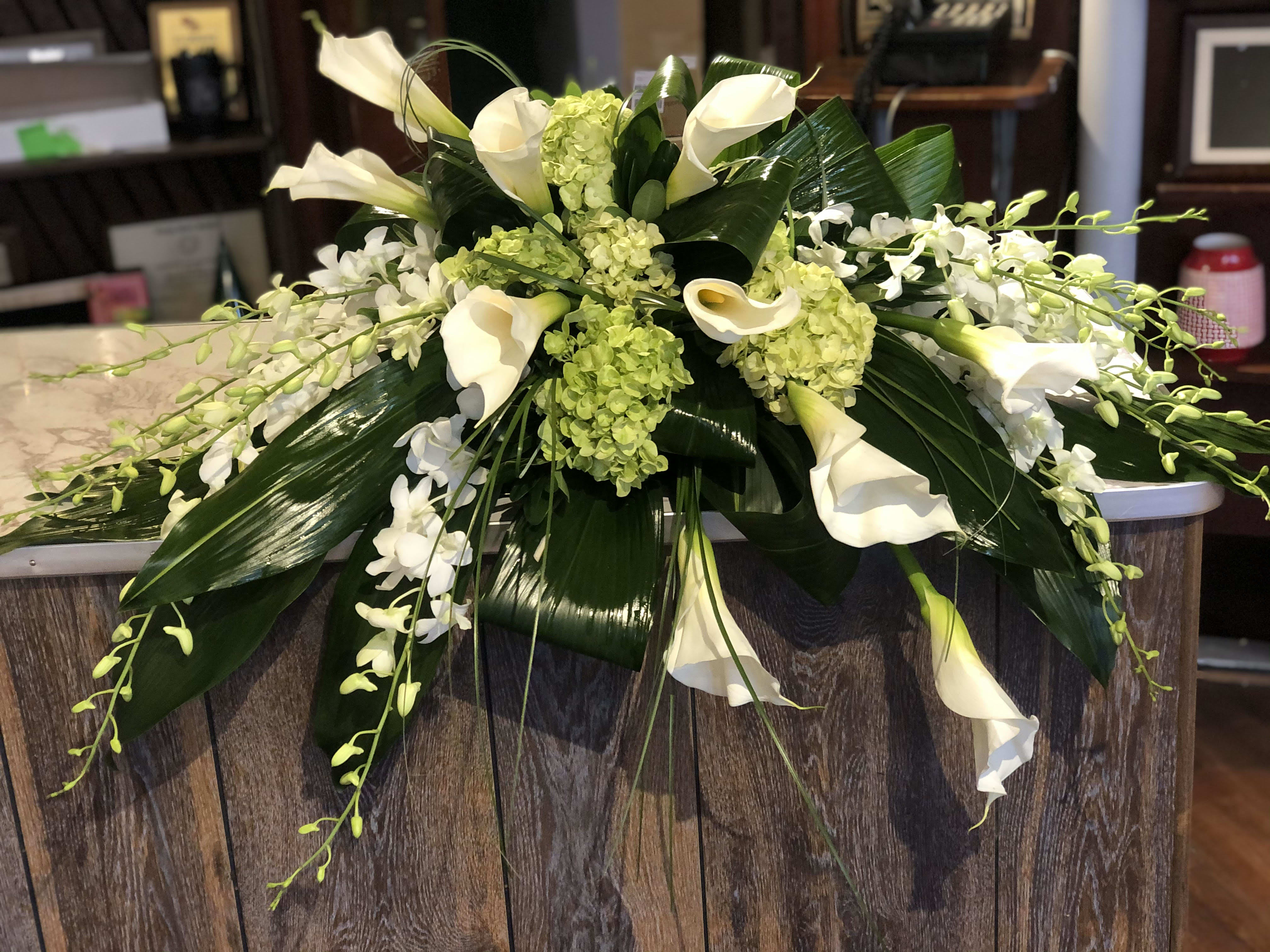 White calla lilies and orchids arranged with green hydrangeas