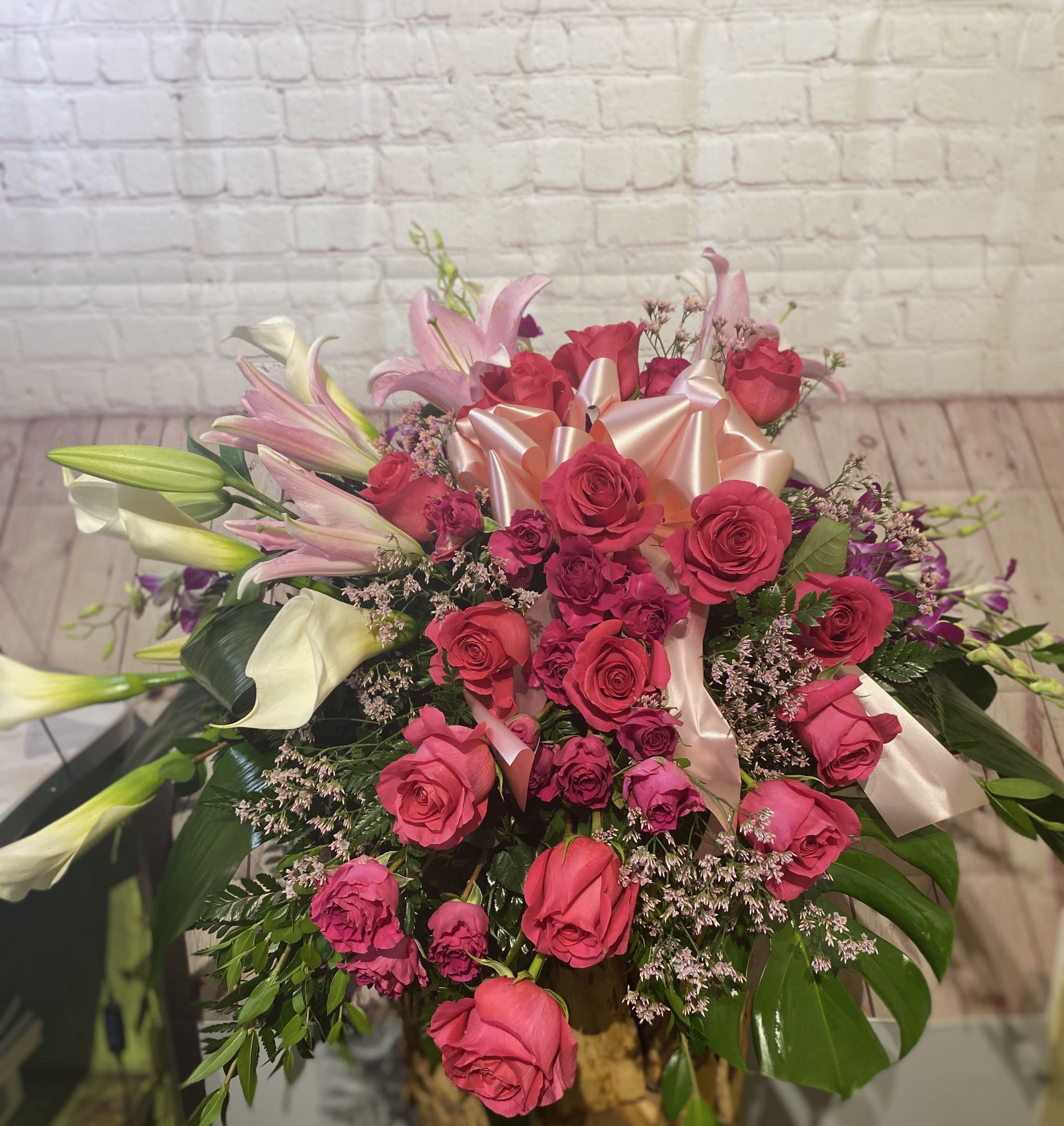Pink roses and lilies arranged with a satin bow.