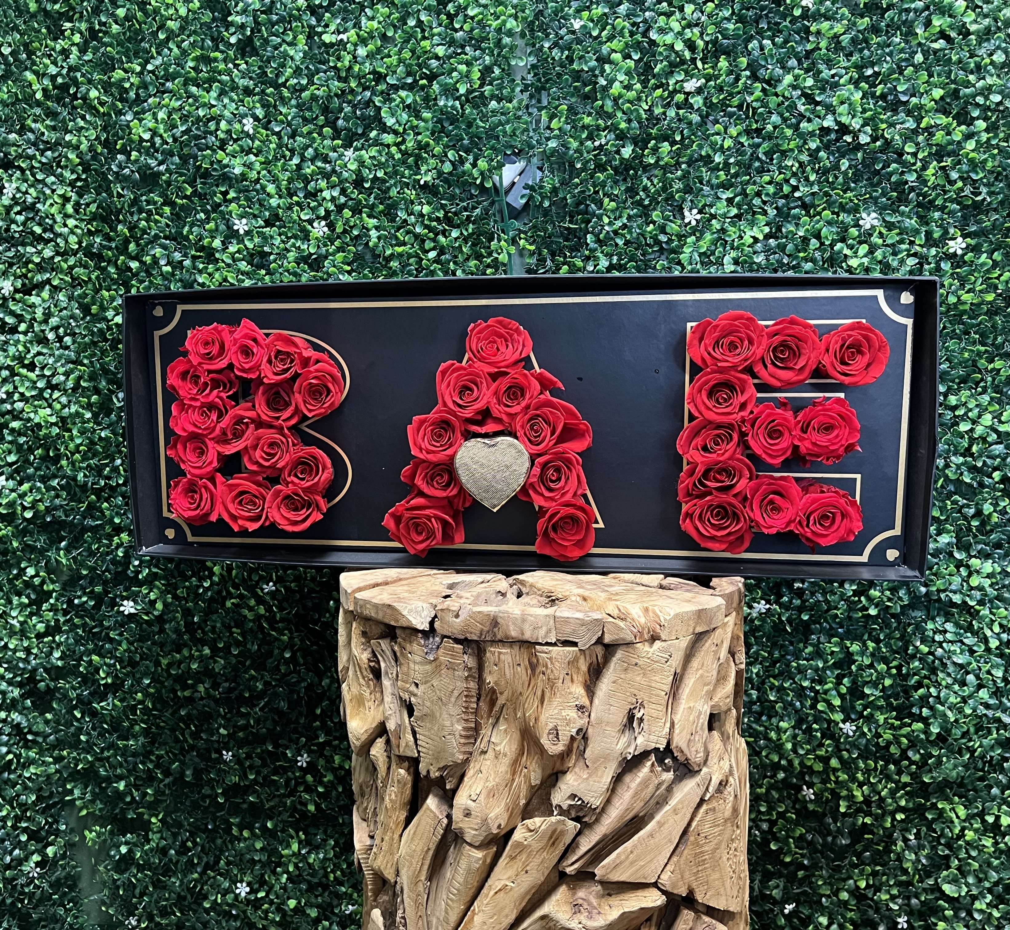 Red roses arranged to spell BAE on a black sign
