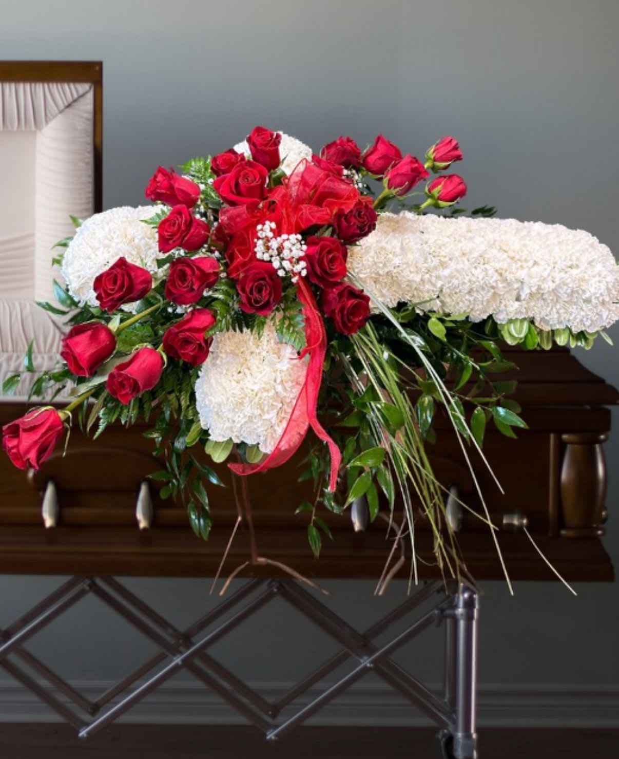 Red roses and white floral spray arranged on a stand