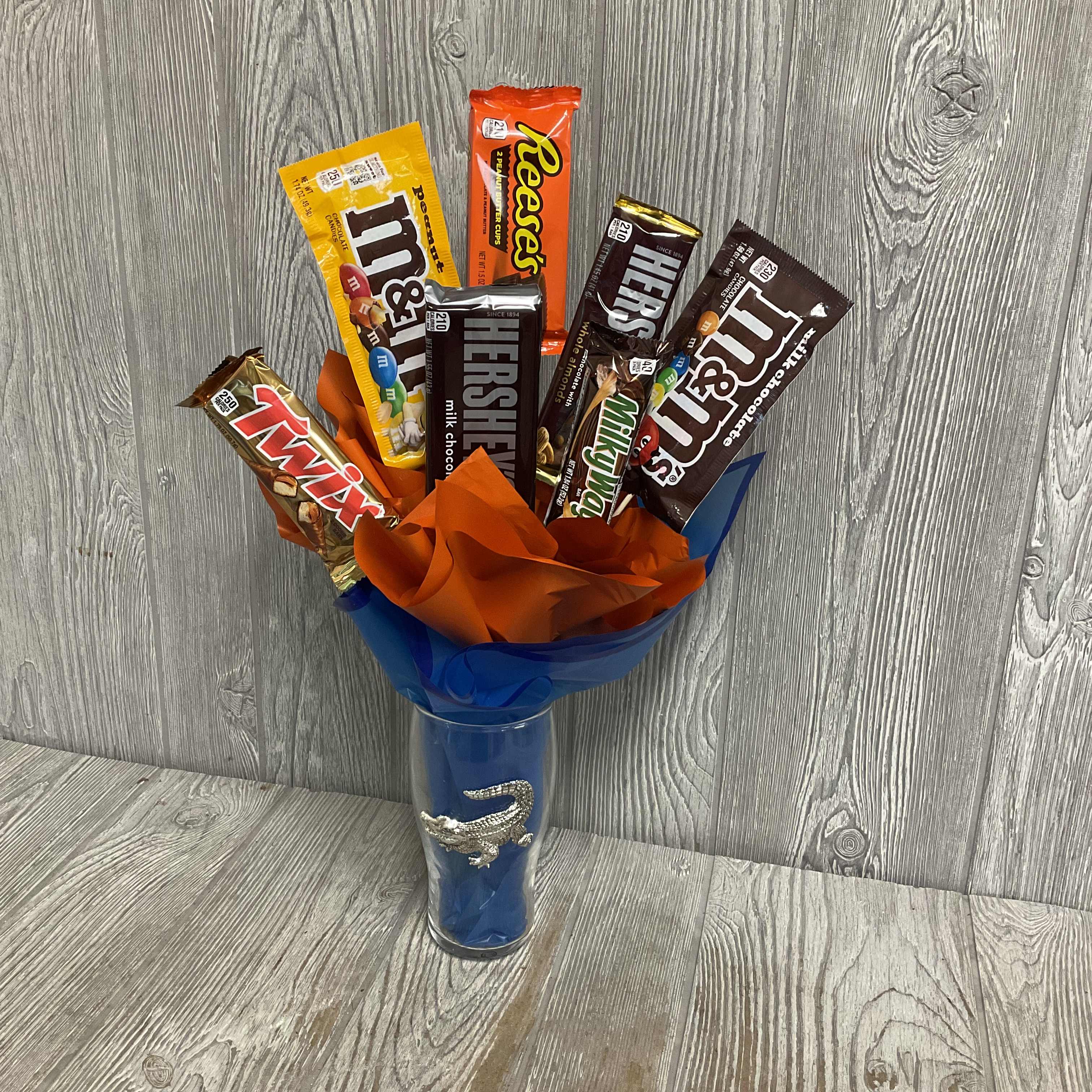 Candy bars arranged in a blue vase with orange and blue wrap