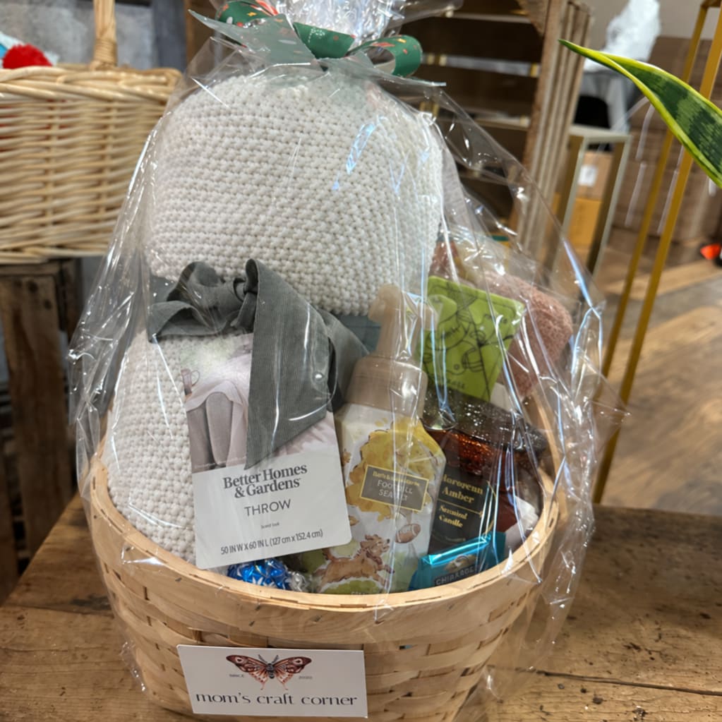 Gift basket with a knitted throw, candles, and small packaged items