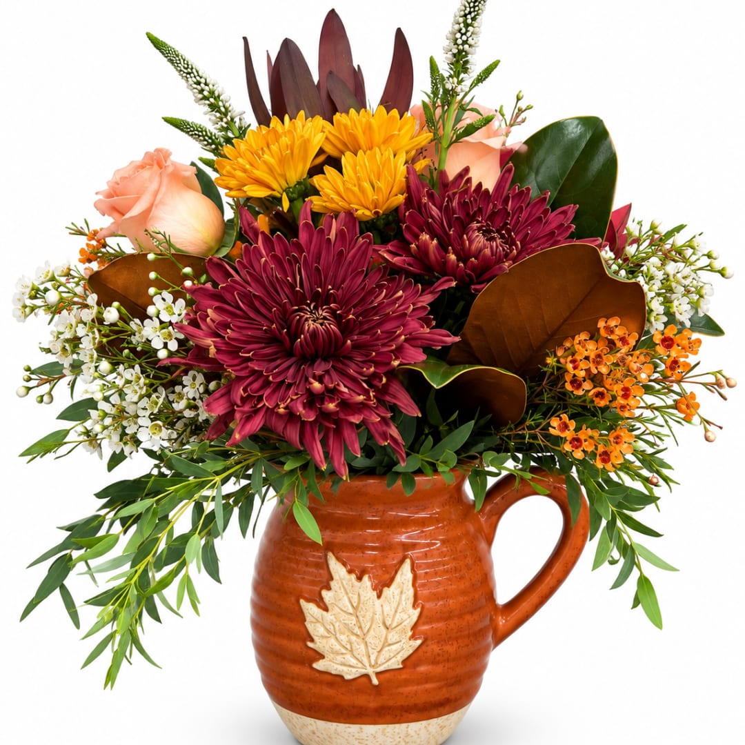 Autumn bouquet in a ceramic pitcher with burgundy, yellow, and peach flowers
