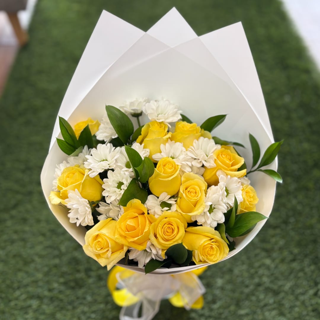 Bouquet of yellow roses and white daisies wrapped in white paper