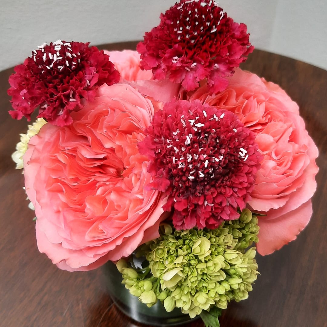 Pink and red floral arrangement in a dark vase