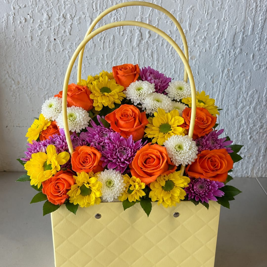 Basket arrangement of orange roses and colorful daisies