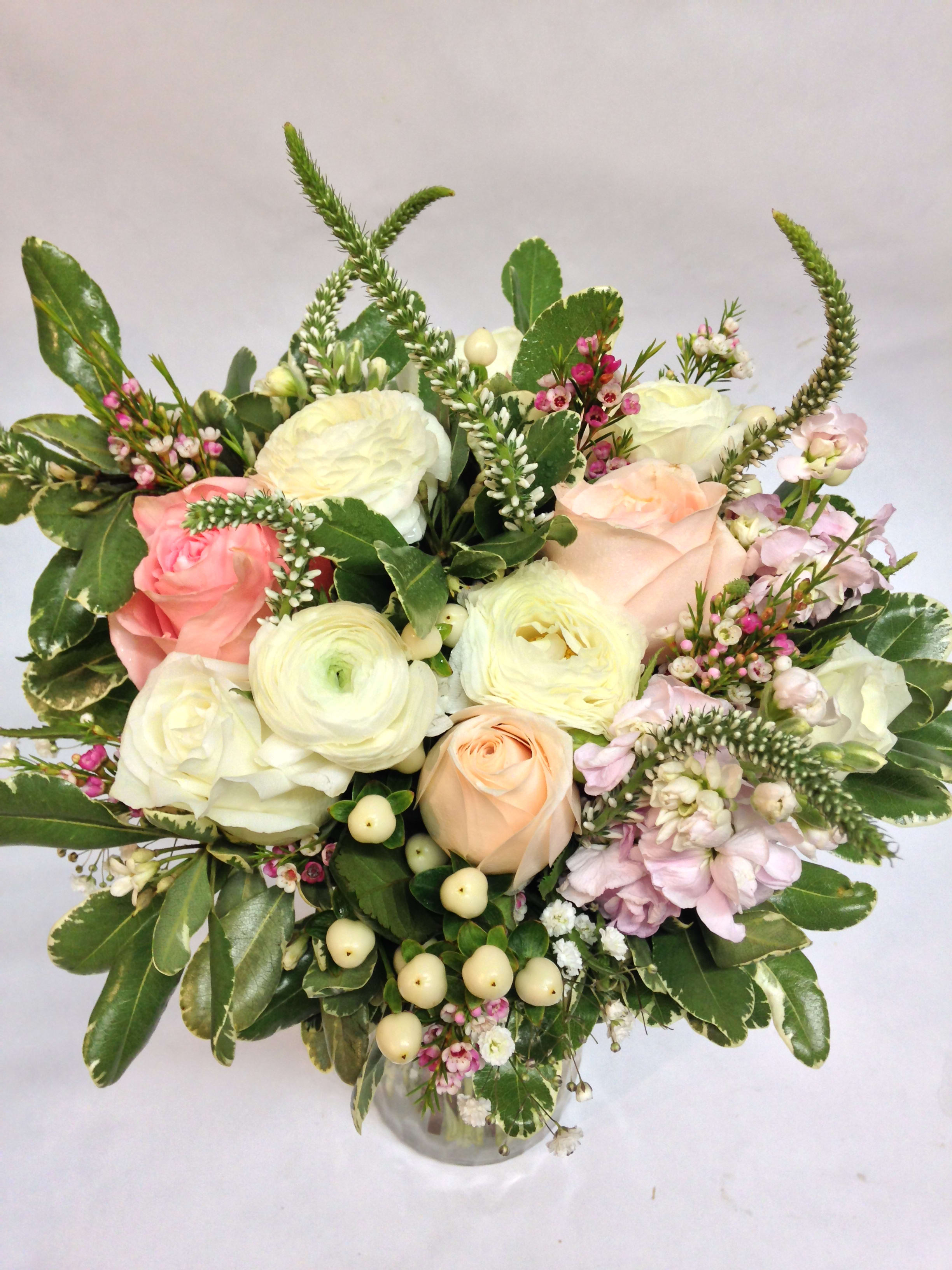 Mixed bouquet of pale roses and white blooms in a glass vase
