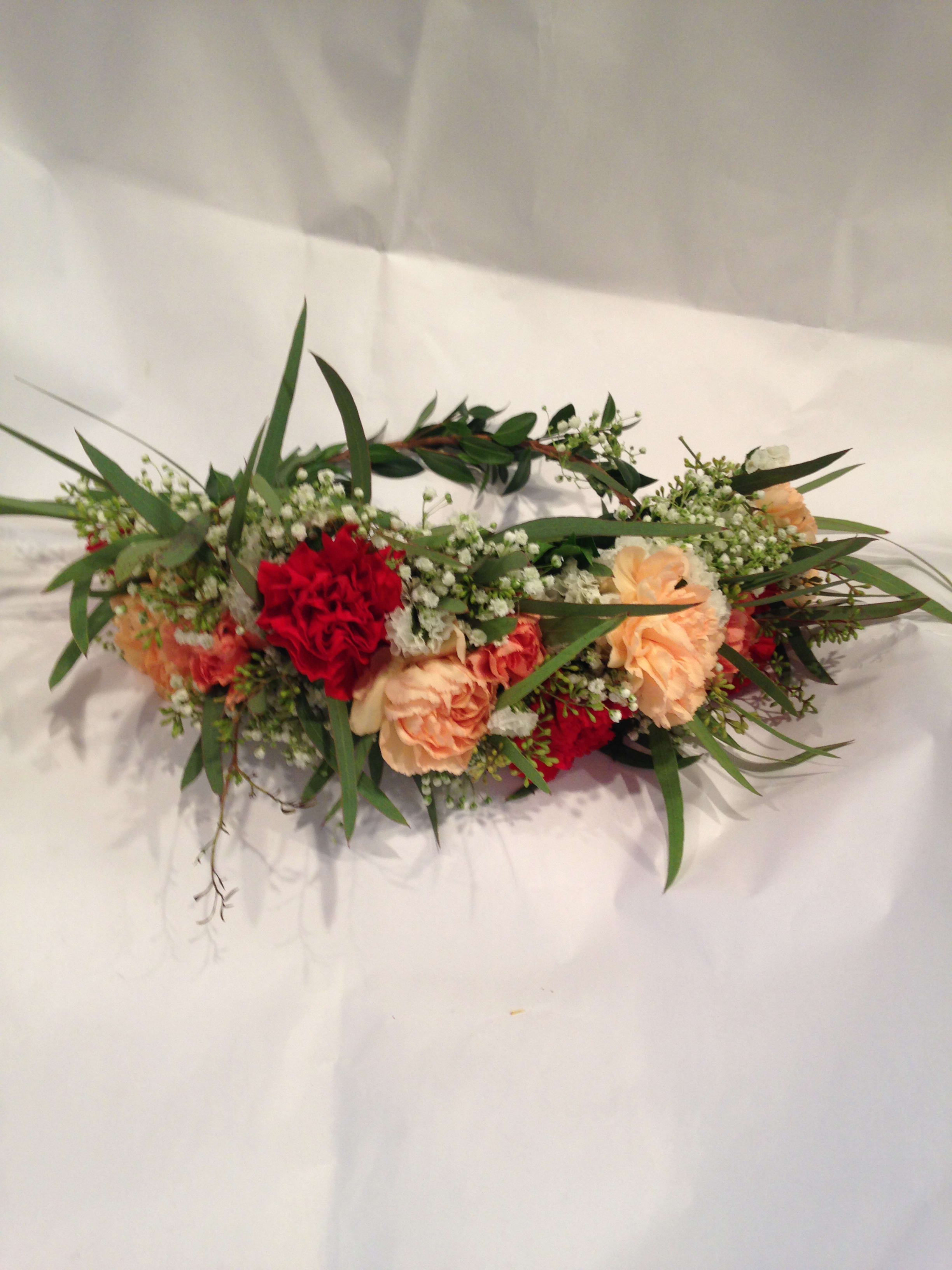 Low floral arrangement with red and peach carnations and greenery