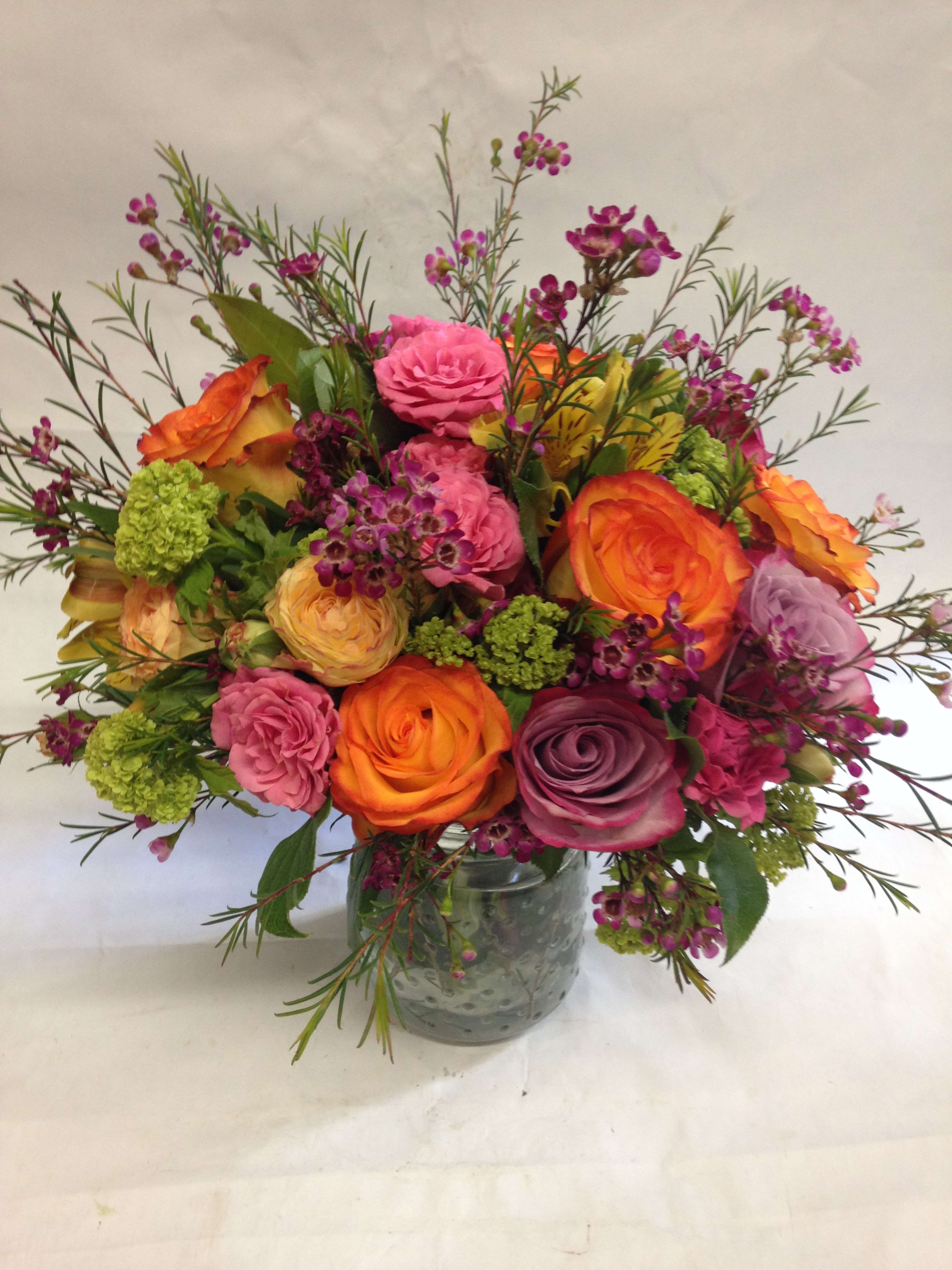 Mixed bouquet of roses and small purple flowers in a glass vase