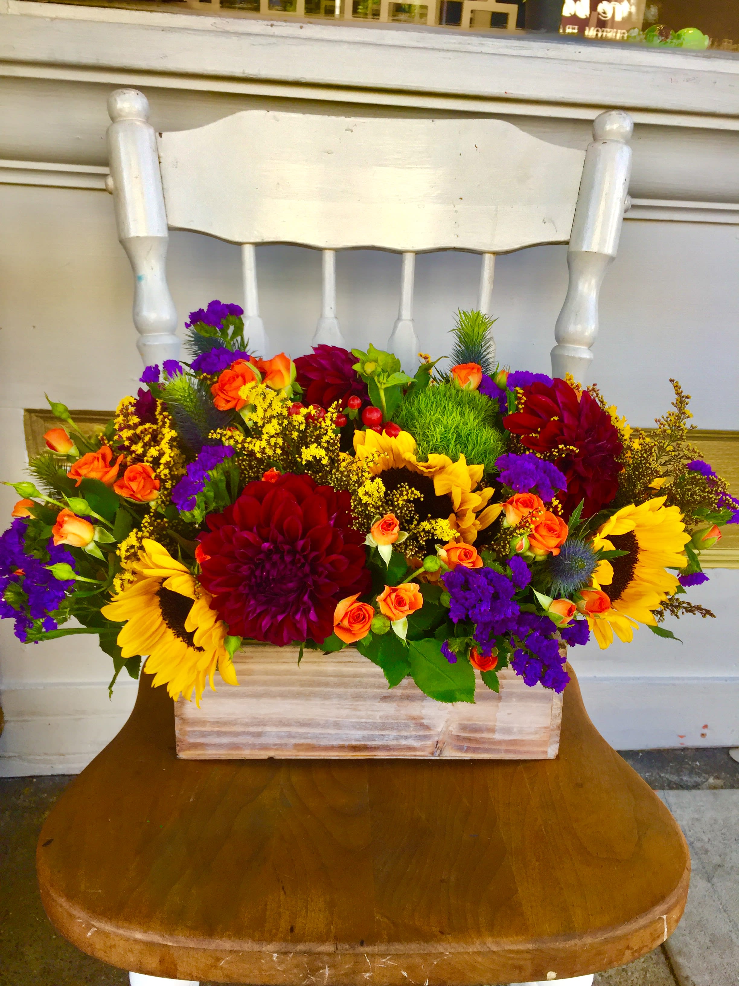 Bright mixed flower arrangement in a wooden box on a chair