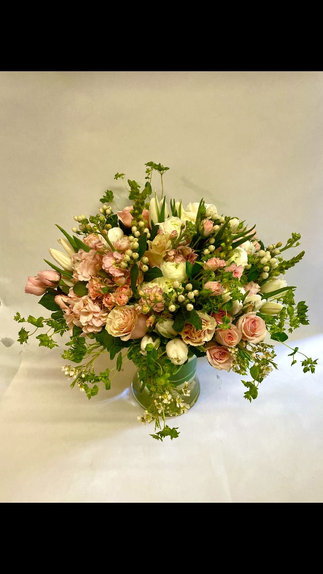 Blush and white floral arrangement in a green vase