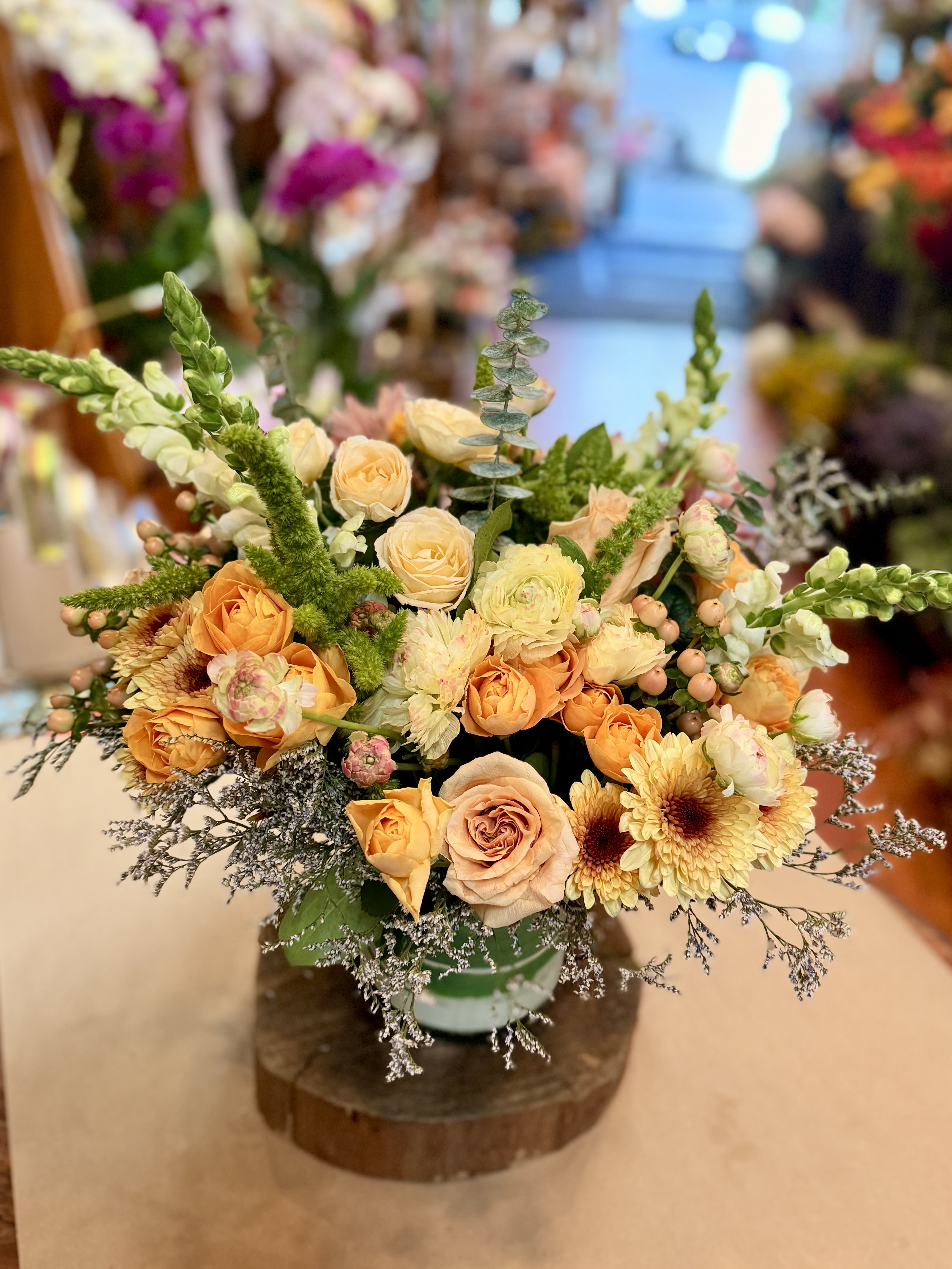 Low floral arrangement of peach roses and pale yellow blooms in a vase