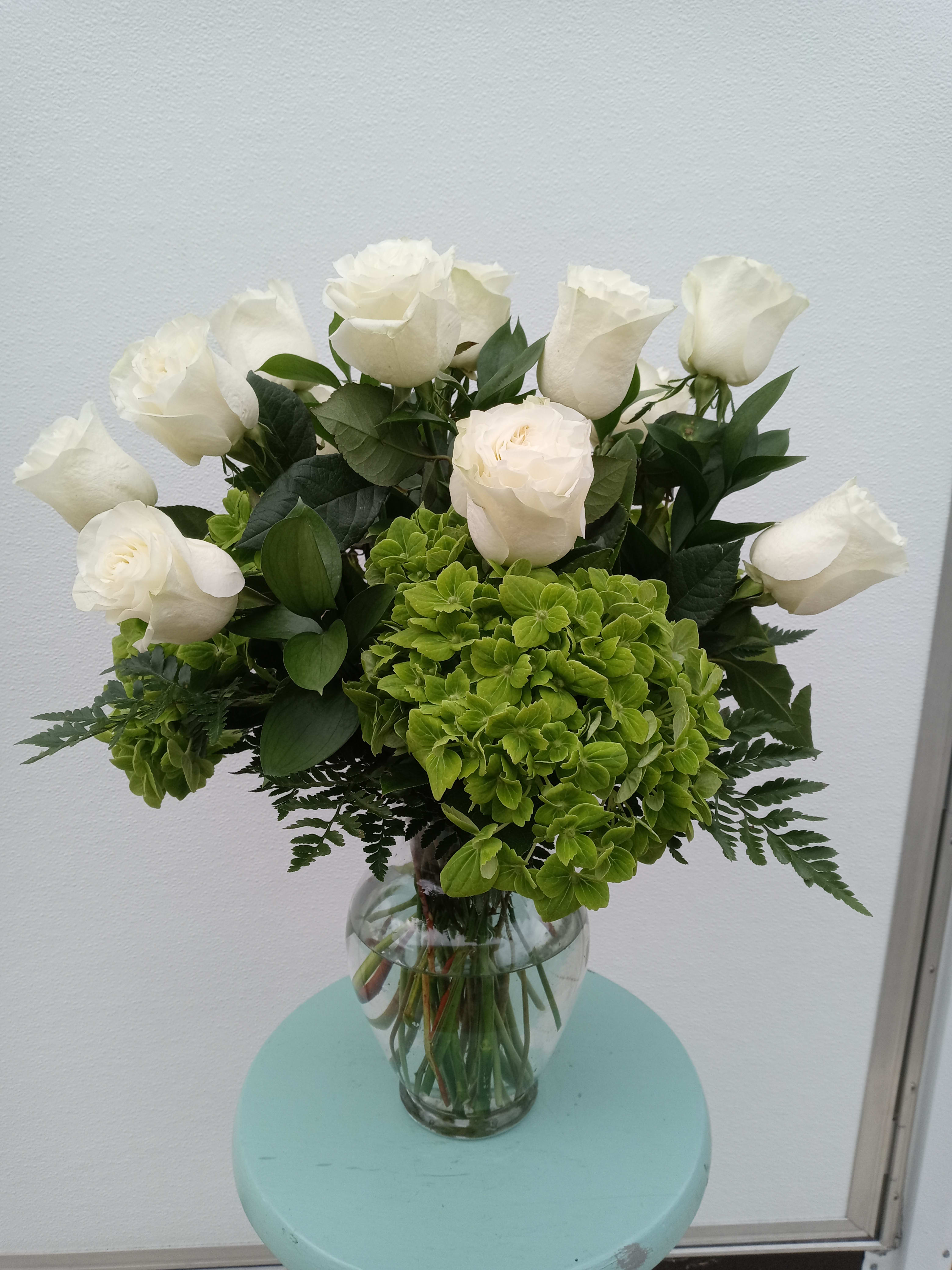 White roses and green hydrangeas in a clear glass vase
