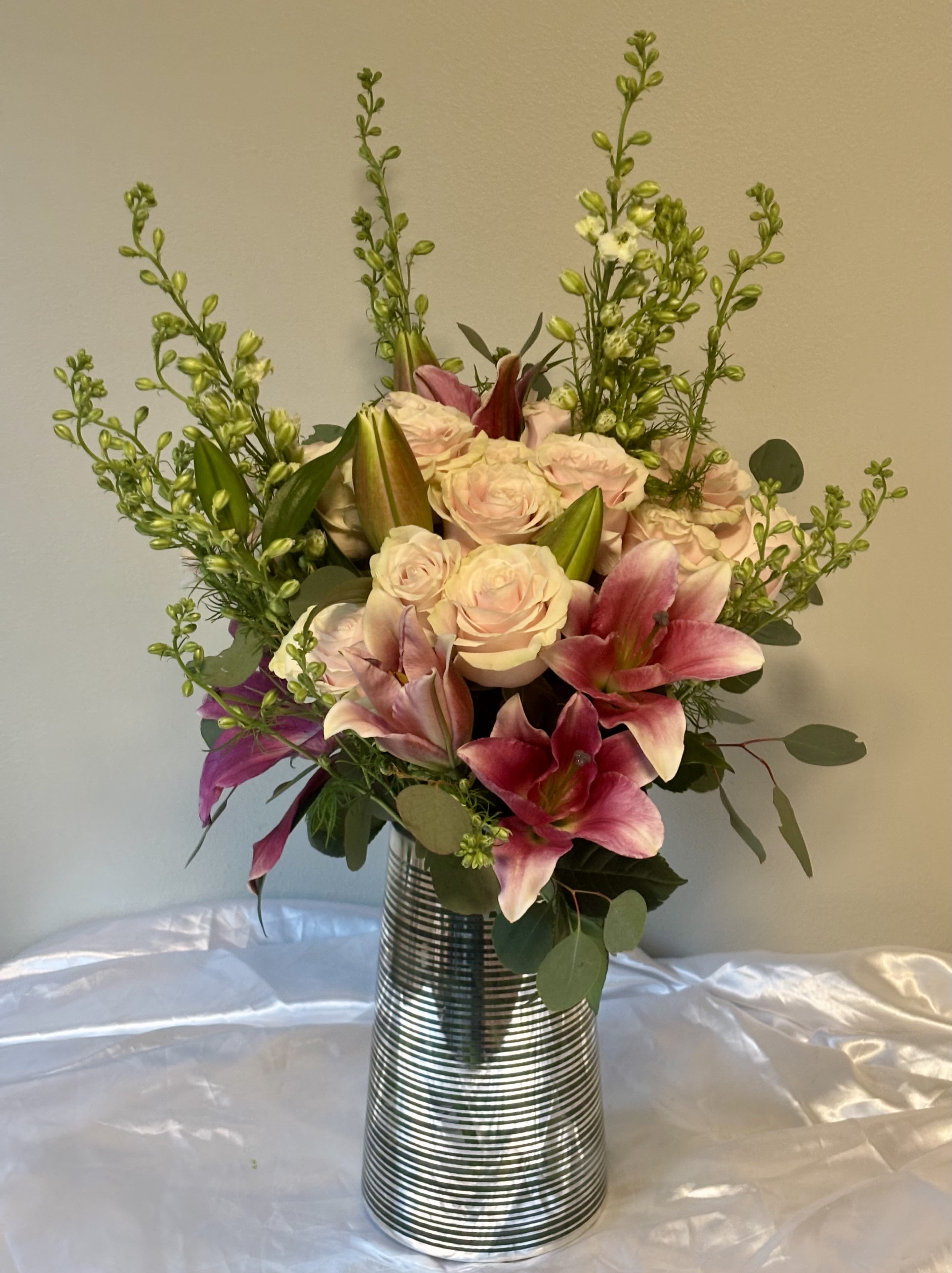 Pink lilies and pale roses arranged in a striped metal vase