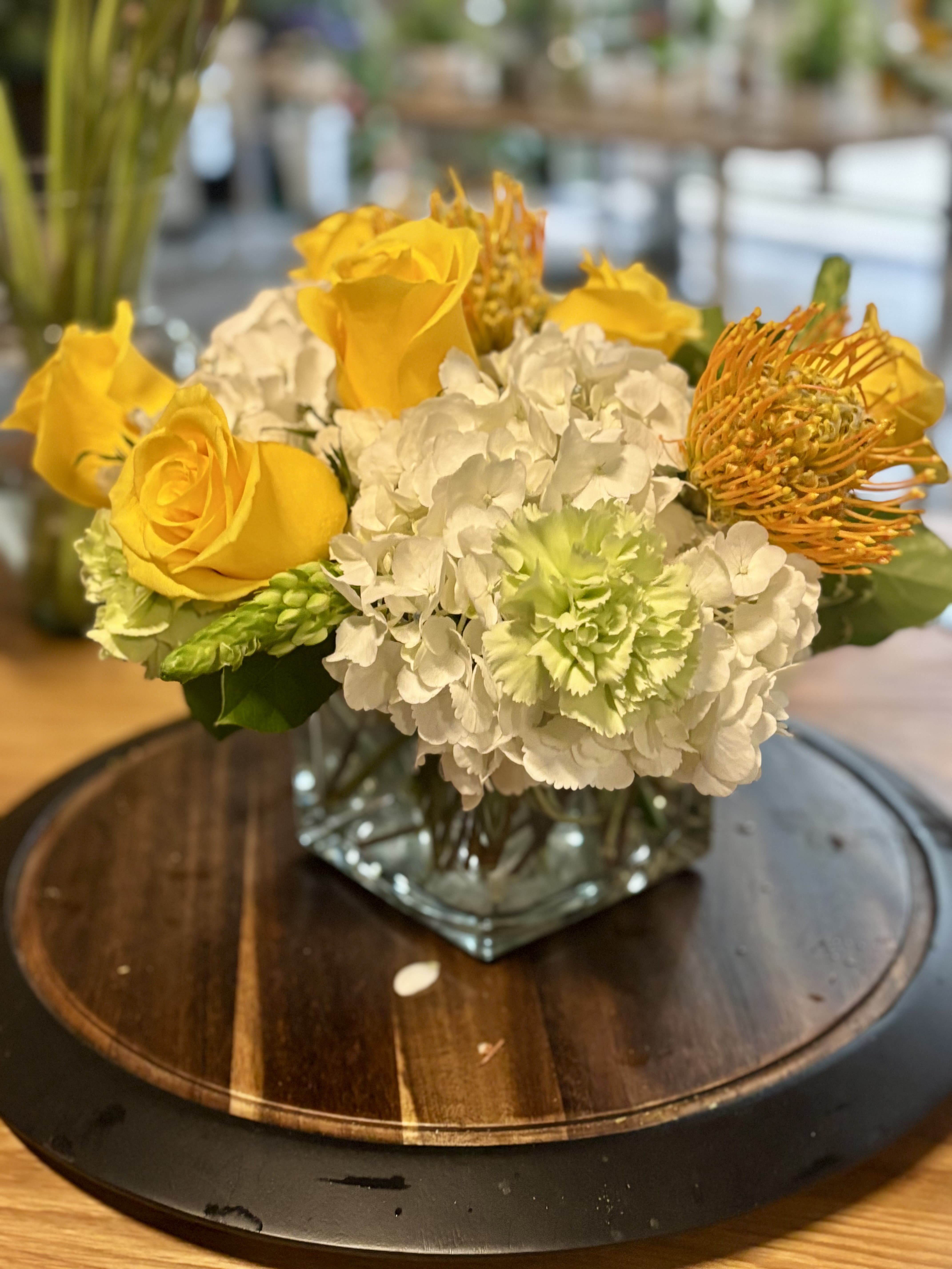Yellow roses and white hydrangeas in a square glass vase
