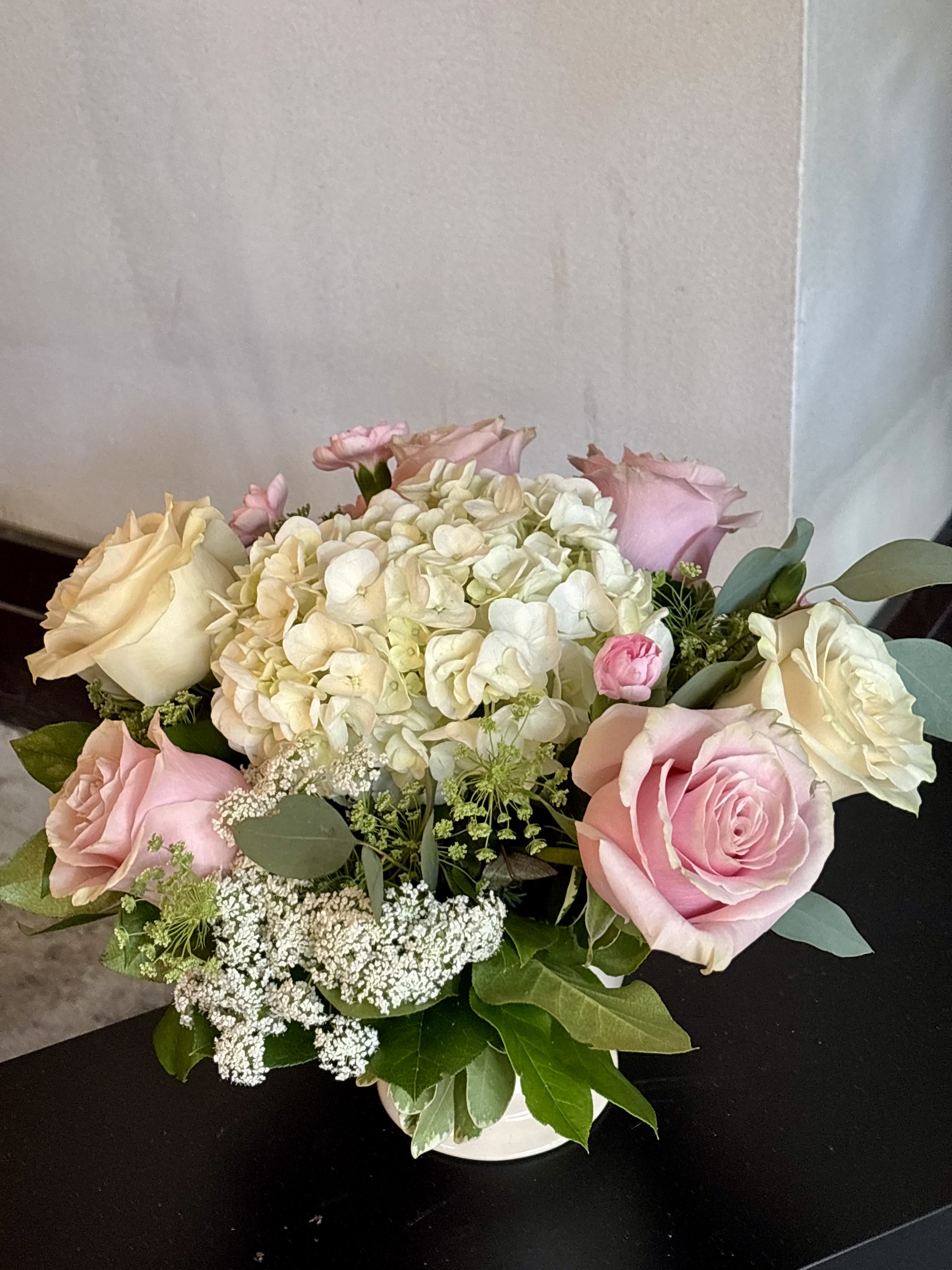 Pink and cream roses with white hydrangea in a low vase arrangement