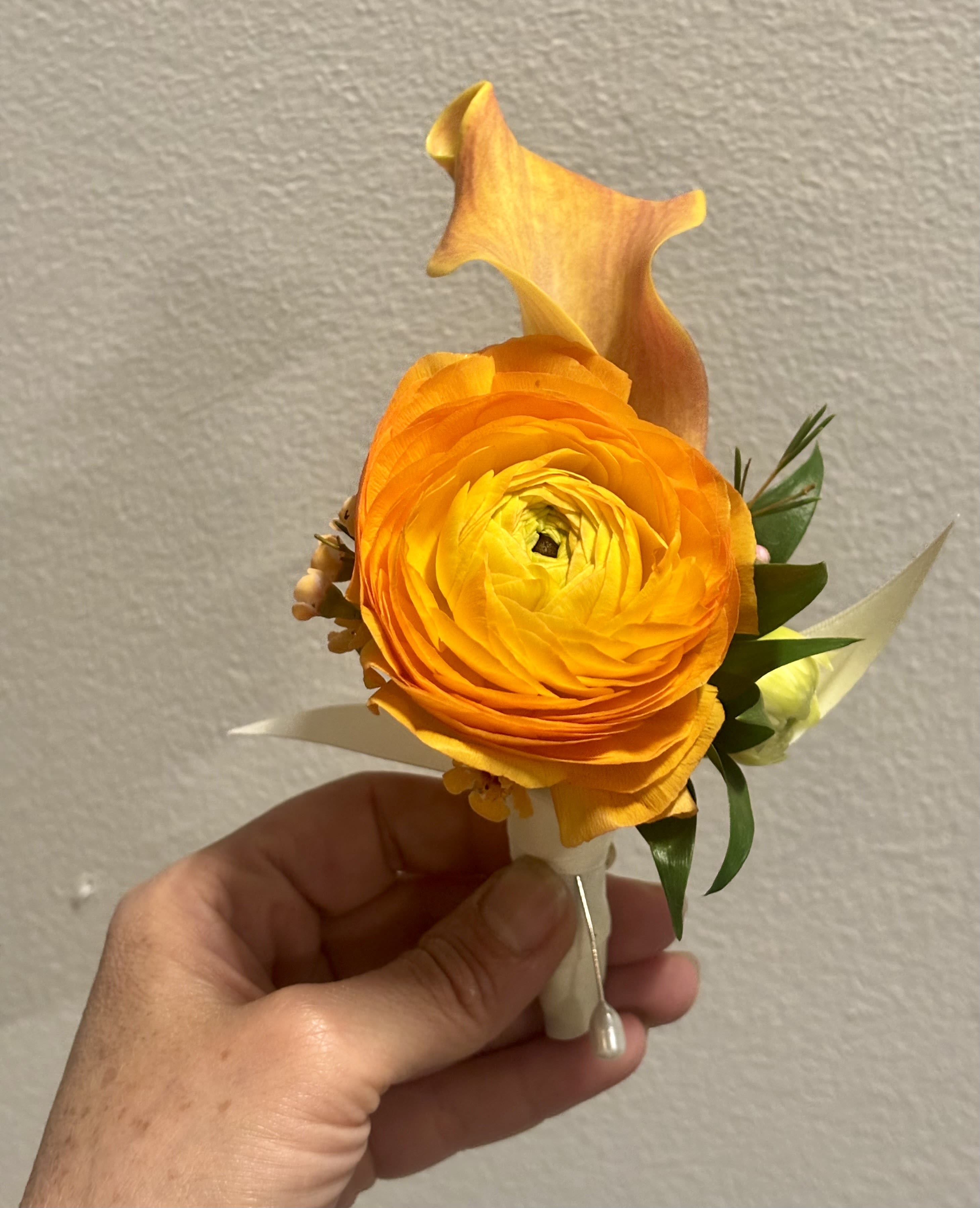 Orange ranunculus boutonniere with a calla lily accent