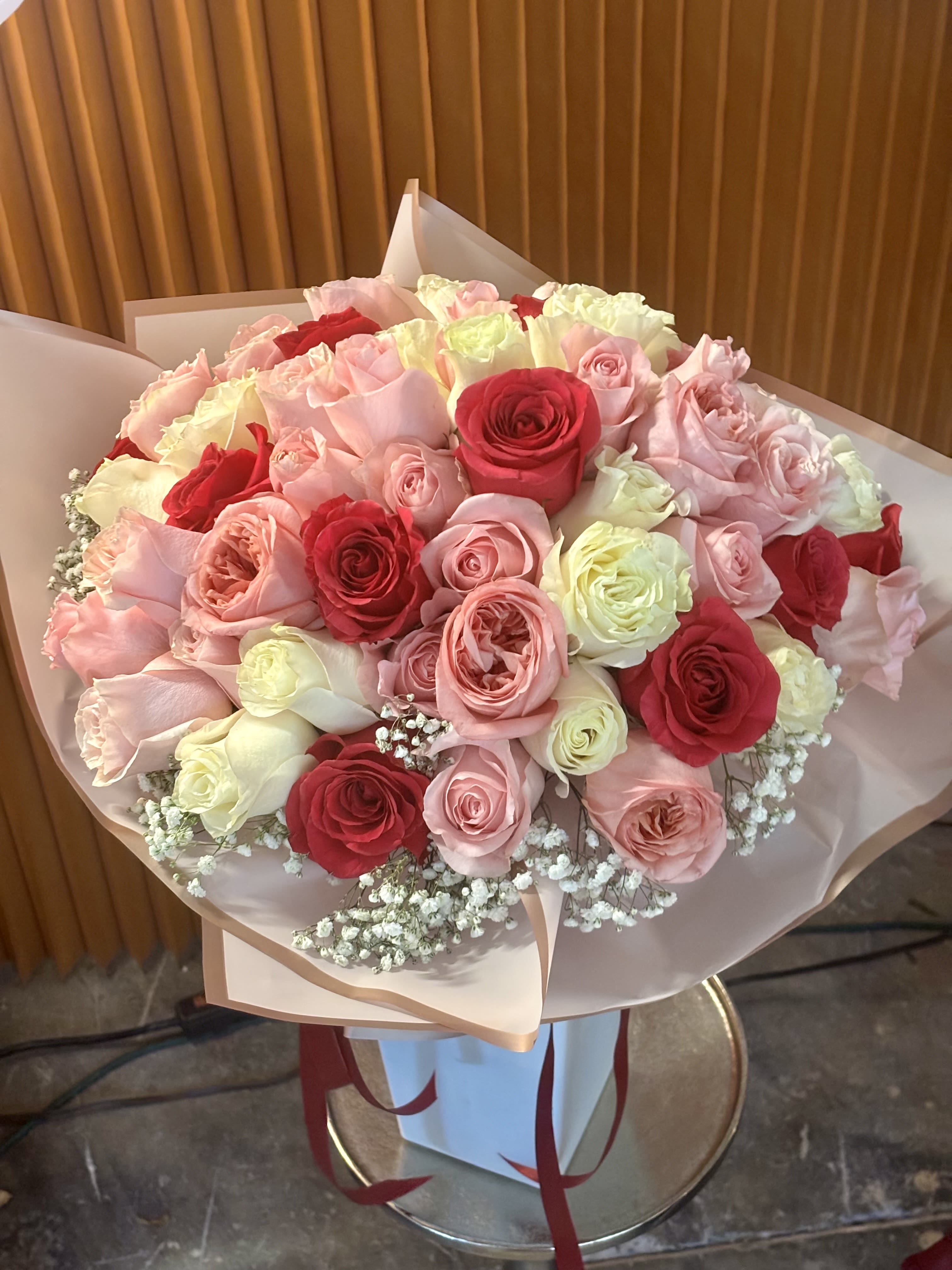 Bouquet of pink, red, and white roses wrapped in pale paper